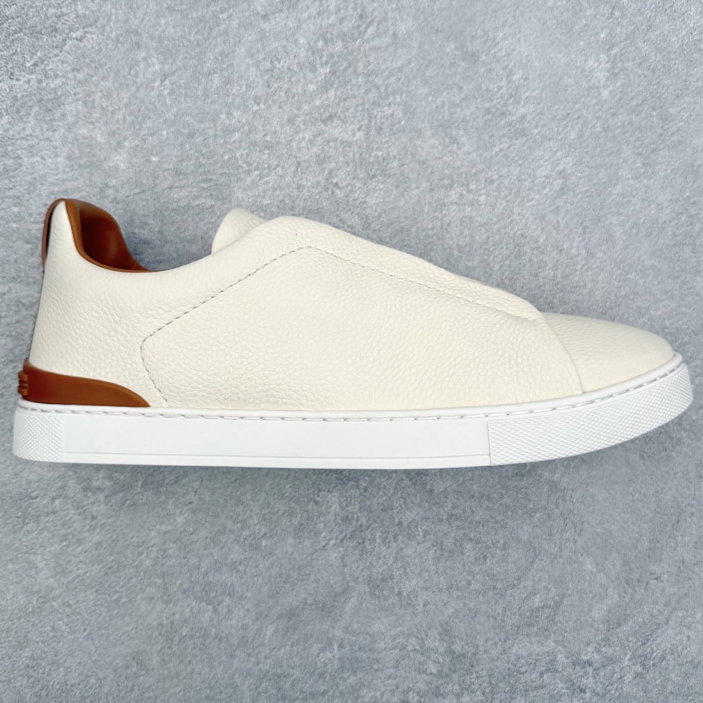 ＃零售版 Zegna Triple Stitch 杰尼亚皮革 圆头平底 低帮低帮运动鞋 摔花纹牛皮制成，饰以丰富的工艺细节，如骆马红棕色皮革嵌饰和手绘饰边。此优雅材质令这款动感十足的运动鞋转变为精致的休闲单品。耐用的橡胶鞋底可探索城市街道提供所有需的支持。版型和产品细节：摔花纹牛皮面料，双色宽罗纹针织鞋带满足不同场合搭配不同风格，小牛皮内裡，鞋垫。内底、徽标压纹皮革中底，高弹力记忆鞋垫和超轻橡胶人字纹防滑鞋底，穿着舒服不凡。鞋底周圈加车大底边线。显得匠心十足。尺码：39 40 41 42 43 44 45 46-选品中心