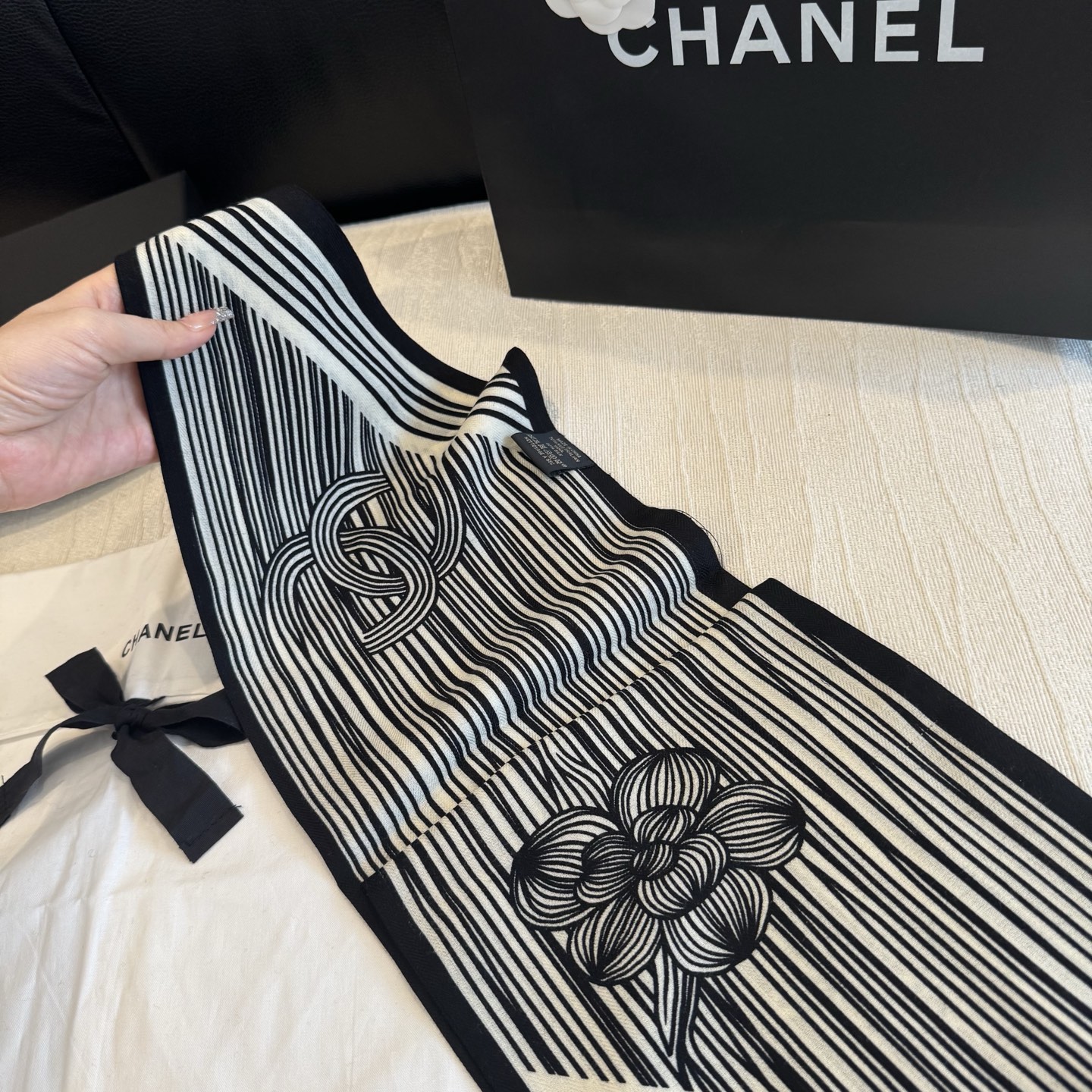 这条是Chanel 2026春夏的黑白线条丝巾，手绘流线纹路搭配山茶花和双C元素，流动性很强，视觉上既利落又柔美。