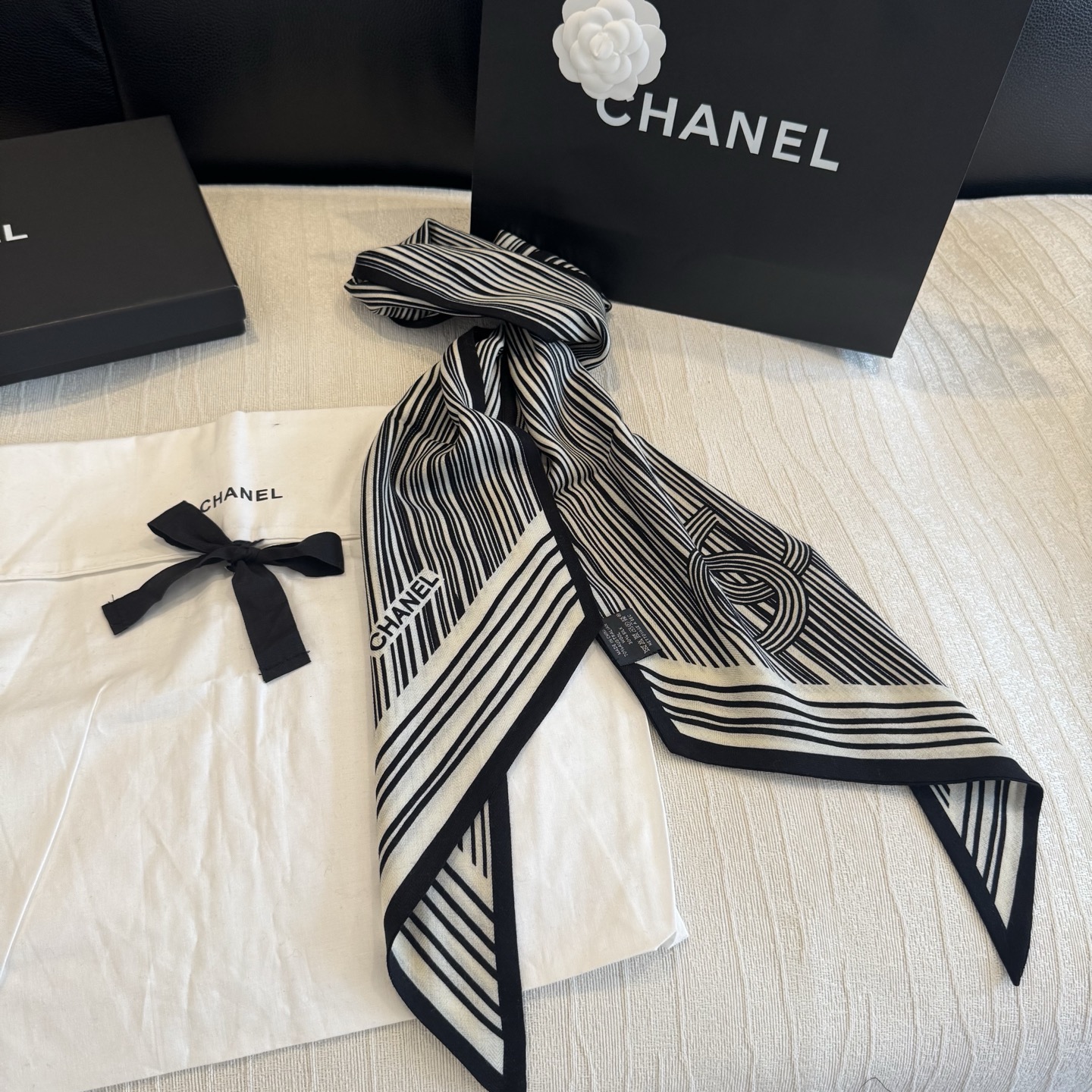 这条是Chanel 2026春夏的黑白线条丝巾，手绘流线纹路搭配山茶花和双C元素，流动性很强，视觉上既利落又柔美。