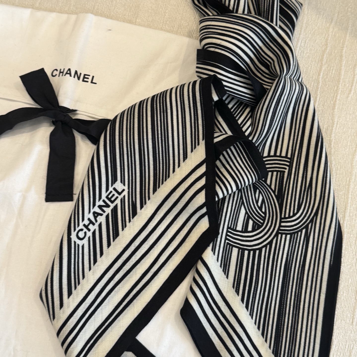 这条是Chanel 2026春夏的黑白线条丝巾，手绘流线纹路搭配山茶花和双C元素，流动性很强，视觉上既利落又柔美。