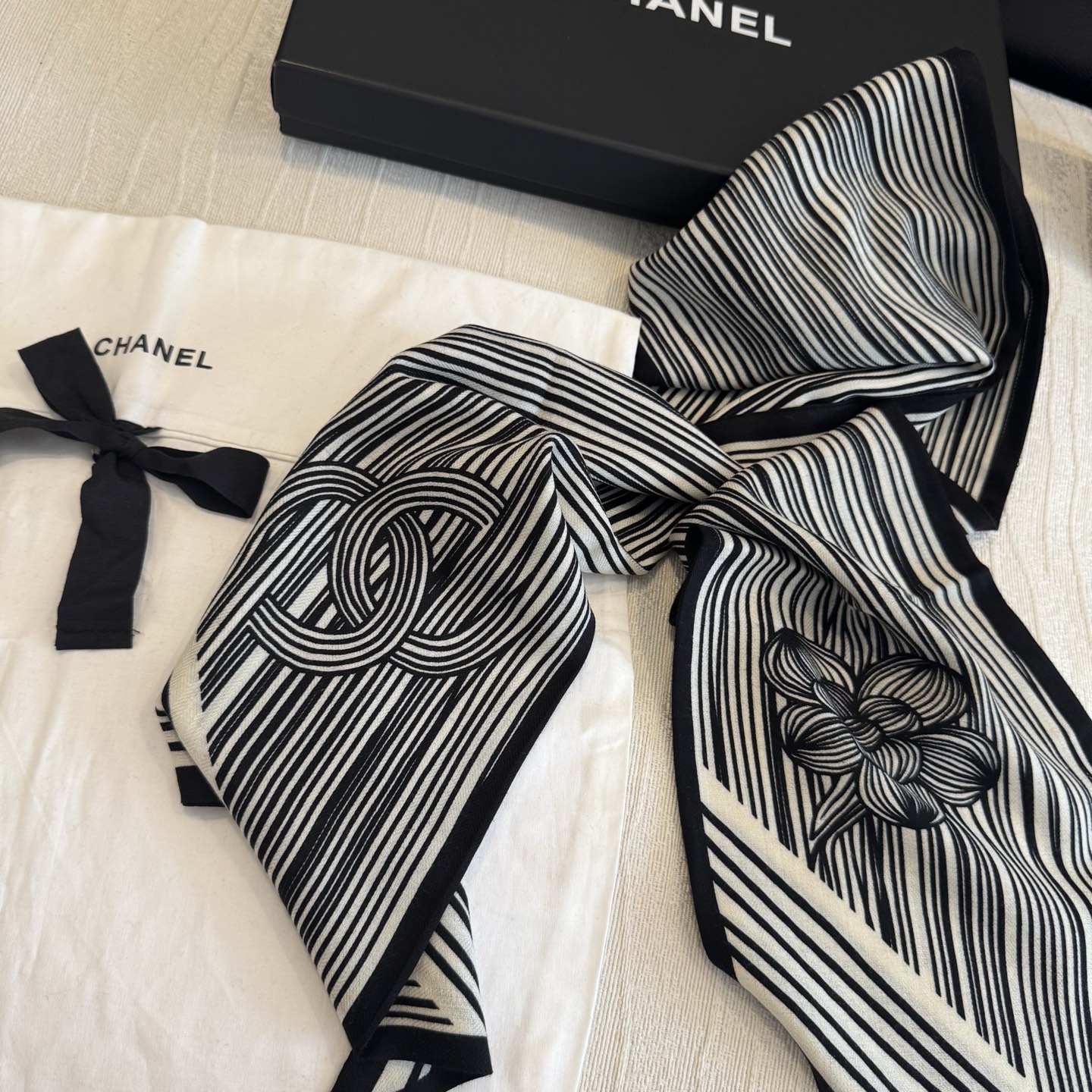 这条是Chanel 2026春夏的黑白线条丝巾，手绘流线纹路搭配山茶花和双C元素，流动性很强，视觉上既利落又柔美。