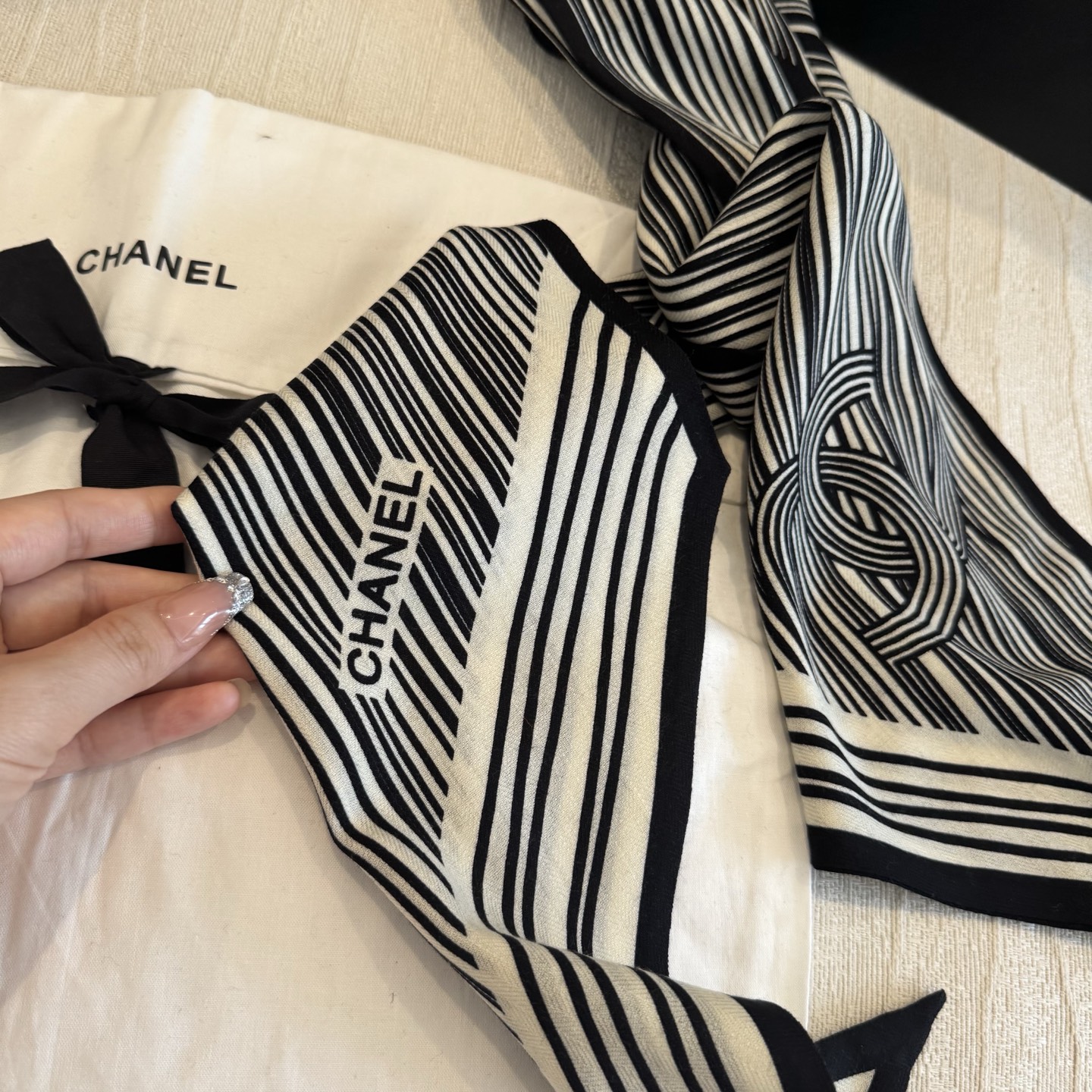这条是Chanel 2026春夏的黑白线条丝巾，手绘流线纹路搭配山茶花和双C元素，流动性很强，视觉上既利落又柔美。
