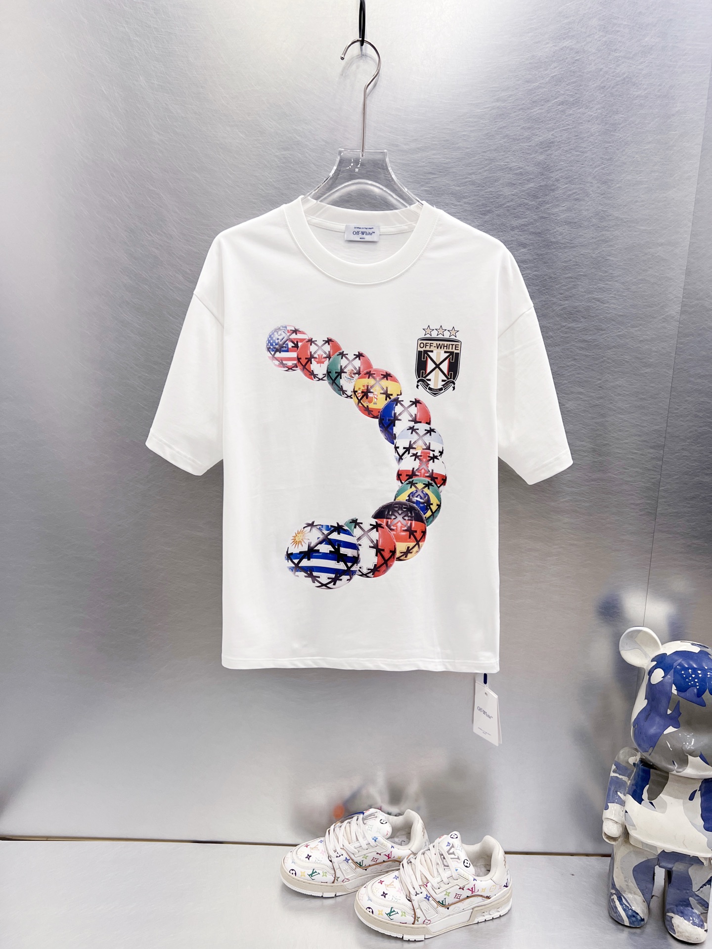 P75 ， OFF-WHITE 多国国旗足球印花短袖 世界杯徽章箭头重磅棉潮牌 T 恤，球迷潮人本命 OW 短袖来了！ 颜色：白色 尺码：S M L XL 整件衣服布满印满各国国旗的足球，每颗球都带有品牌标志性交叉箭头…