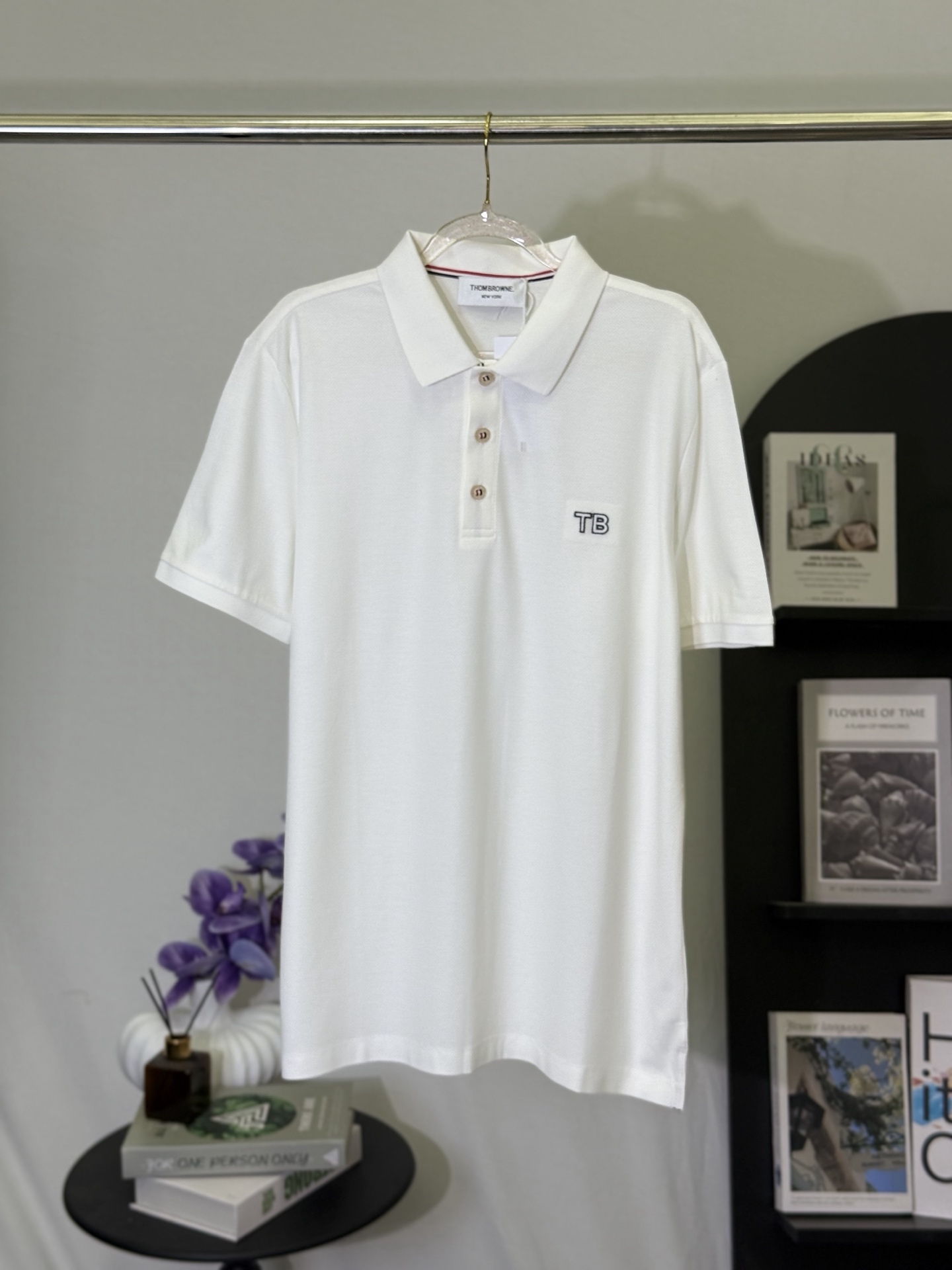 P150💋 Thom Browne Polo con logo TB sobre fondo blanco. Lleva la elegancia y precisión del estilo académico americano a…