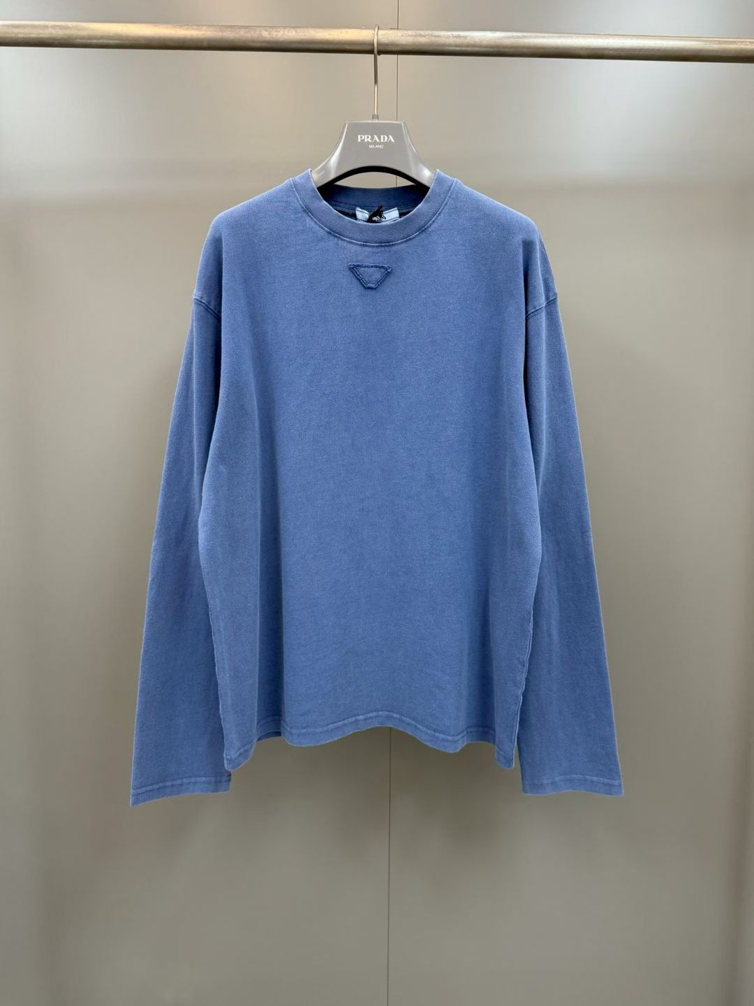 NO:779427,Prada 26ss new triangle patch round neck long-sleeved T-shirt is made of combed cotton and woven with 15 thick yarns. The weight is as high as g. It ensures the stiffness and structure of the fabric while giving the clothes a solid drape and durability.  The ready-made garments are processed through the frying process. Through multiple processes such as pre-shrinking, dyeing, frying, and color fixation, the indigo color presents a natural old-fashioned smudged effect, and the cloth surface forms a richly layered retro texture. At the same time, the moisture absorption and breathability performance of the cotton fiber is enhanced.  Wrinkle-resistant, classic dropped shoulder sleeves and ribbed crew neck. On the basis of retaining a casual and relaxed feel, it is decorated with precision stitching and triangular patches to convey low-key and luxurious Italian craftsmanship aesthetics. It is a basic item with both practical wearability and style!  ,Prada-clothing,prada,tees,t-shirt,19860909普拉达26ss新款三角贴饰圆领长袖T恤 采用精梳棉为原料,选用15支粗支纱线织造,克重高达g,在保证面料挺括度与结构感的同时,赋予衣物扎实的垂坠感与耐穿度 成衣经炒色工艺处理,通过预缩、染色、炒色、固色等多道工序,使靛蓝色泽呈现自然的做旧晕染效果,布面形成层次丰富的复古肌理,同时强化了棉纤维的吸湿透气性能与抗皱性,经典落肩袖型搭配罗纹圆领,在保留休闲松弛感的基础上,通过精密车线与三角贴布装饰,传递出低调奢华的意式工艺美学,是兼具实穿性与风格感的基础款单品！,普拉达-服装,prada,tees，t-shirt,,Women's clothing