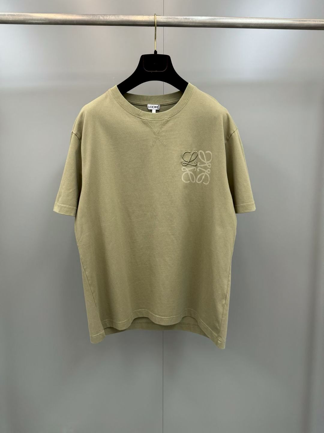 NO:779399,Loewe 26ss new embroidered round neck short-sleeved T-shirt is based on combed cotton and is woven with g-heavy plain knitting. The fabric texture is solid and delicate, with a crisp drape and moisture-absorbing and breathable performance. It is suitable for daily wear in many scenarios.  The ready-made garments are treated with a slight color frying and washing process. On the basis of retaining the original texture of the cotton fiber, the garments are given a soft and aged smudged layer, weakening the stiffness of the new garments and presenting a retro and relaxed visual tone.  The X-shaped jujube reinforcement process is used at the neckline to strengthen the anti-deformation ability of the rib collar and extend the wearing life; the left chest area uses flat embroidery technology to present the brand logo three-dimensionally, with fine and full stitches, and matching dark patterns with same-color printing. It creates a low-key and luxurious visual hierarchy through light and dark contrast, and injects exquisite craftsmanship details into the basic style, which is both practical and high-end!  ,Loewe-clothing,loewe,T-shirt,tees,t-shirt,19860909罗意威26ss新款刺绣圆领短袖T恤 以精梳棉为基底,采用g重磅平纹针织织造,布面肌理扎实细腻,兼具挺括垂坠感与吸湿透气性能,适配多场景日常穿搭 成衣经轻微炒色洗水工艺处理,在保留棉纤维原生质感的基础上,赋予色泽柔和的做旧晕染层次,弱化新成衣的生硬感,呈现复古松弛的视觉调性 领口处采用X型打枣加固工艺,强化罗纹领的抗变形能力,延长穿着寿命；左胸区域以平绣工艺立体呈现品牌标识,针脚细密饱满,搭配同色系扒印暗纹,通过明暗对比营造低调奢华的视觉层次,在基础款型中注入精致工艺细节,兼具实穿性与高级感！,罗意威-服装,loewe,T-shirt,tees，t-shirt,,Women's clothing