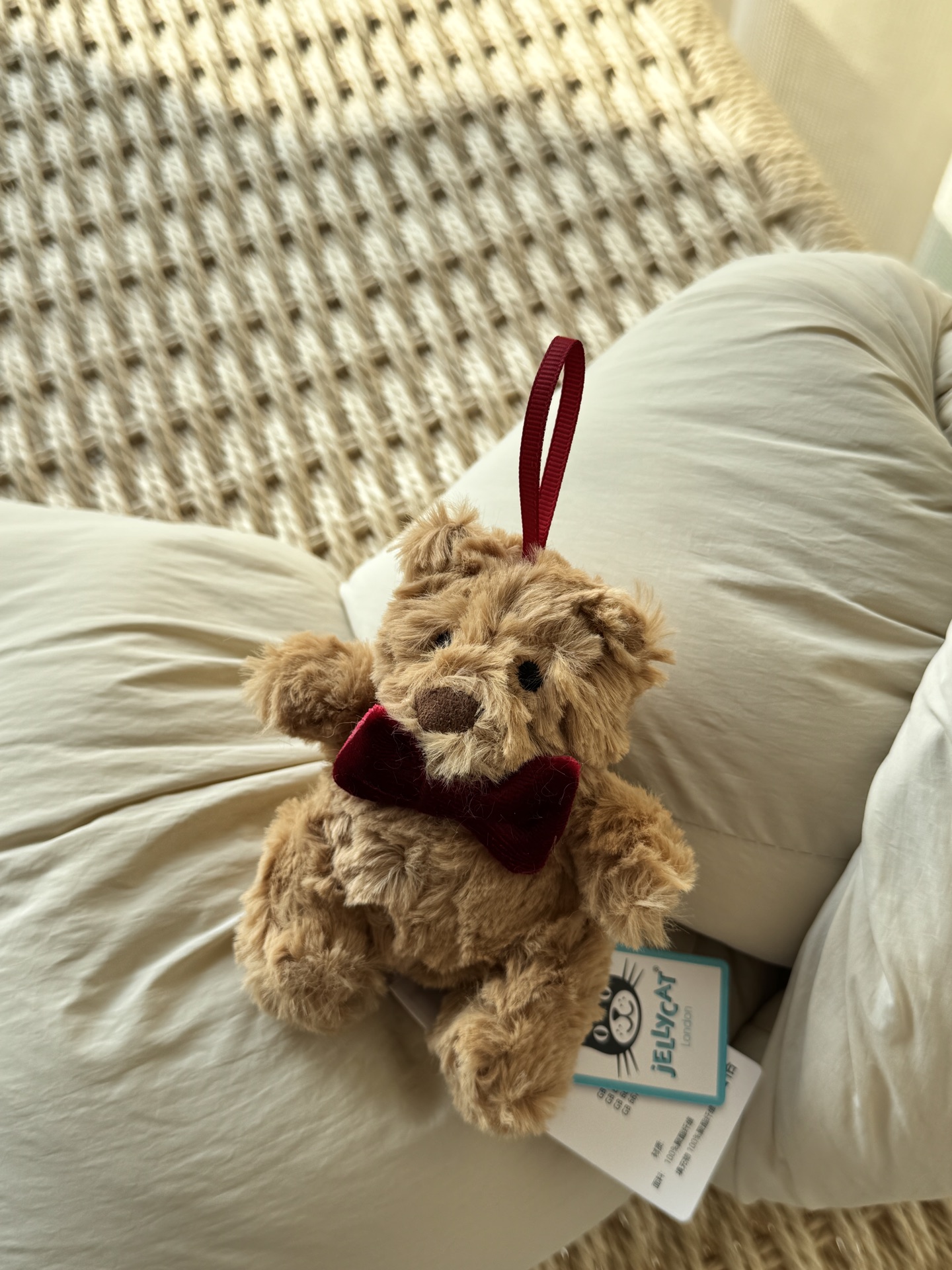 NO:810298,It's coming!  Jellycat's new Christmas Barcelo Bear winter ornament has arrived at your happy planet ahead of schedule!  Light brown fluff wraps the cute figure, and a classic burgundy bow is embellished around the neck, instantly lighting up the holiday atmosphere. The lanyard on the head is an invitation prepared for all beautiful scenes - hang it on a backpack to accompany you on your commute and stroll; hang it on the top of the Christmas tree to protect the warm corner of your home; or as a heartfelt gift, send soft and cute blessings directly to you. Jellycat doll from trendy department store, backpacks19860909它来了！Jellycat 圣诞新品巴塞罗熊冬日挂饰,已提前抵达你的快乐星球！ 浅棕色绒毛裹着憨萌身形,一抹经典酒红蝴蝶结在颈间点缀,瞬间点亮节日氛围.头顶的挂绳,是为所有美好场景准备的邀请函—— 挂在背包上,陪您通勤漫步；悬于圣诞树梢,守护家中的温馨一角；或作为一份饱含心意的礼物,将软萌祝福直接送达.,潮品百货Jellycat公仔,backpacks,accessory