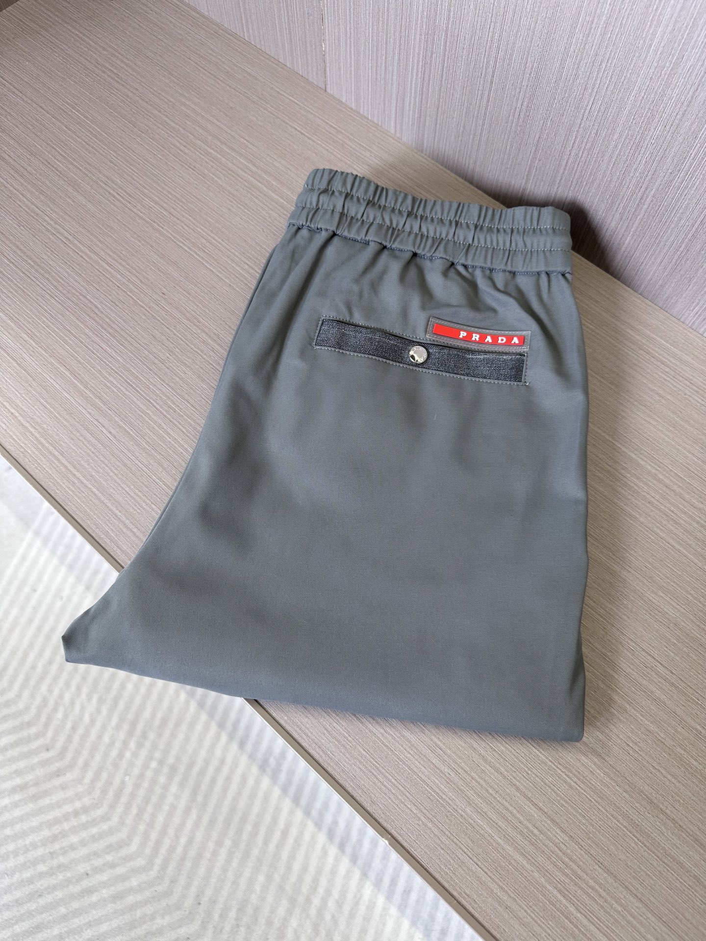 NO:155774,PRA25SS spring and summer new lightweight twill cotton drawstring casual pants, men's metal triangle nameplate pendant fashionable versatile straight casual pants!  Trading companies have sparse channels and are on sale on the leading official website!  With its unique fabric selection, clever design concept and exquisite style cutting, P home's new casual pants have become an ideal choice for urban people who pursue both fashion and comfort!  This trouser is made of a light and light twill cotton cloth customized by customers. It not only feels soft but also is breathable. Even when worn in hot summer, it can bring a comfortable and comfortable experience!  The front and back pockets are cleverly integrated with the splicing elements of denim fabric, forming a sharp contrast with the trouser body, which not only adds visual layering but also highlights the uninhibited denim style!  The triangle nameplate pendant at the front waist sways in the wind, and the metallic luster shines in the sun, which not only enhances the overall texture of the pants, but also reveals a low-key luxury!  The red rubber nameplate on the back pocket is in sight, and the bright colors form a strong contrast with the calm trouser body, becoming the finishing touch of the whole trouser outfit, silently demonstrating the wearer's luxury identity!  The drawstring elastic waist design is not only easy to put on and take off, but also freely adjusts the tightness according to the personal waist circumference to ensure the best wearing experience!  The straight-leg cut not only retains the ability and neatness of business pants, but also does not lose the casual pants' casualness!  Size M-3XL M size waist 78/84cm-hip circumference 98cm-front 28cm-thigh circumference 60cm-trouser length 101cm-trouser legs 33cm L size waist 82/88cm-thigh circumference 102cm-front 29cm-thigh circumference 62cm-trouser length 102cm-trouser legs 34cm XL size waist 86/92cm-thigh circumference 106cm-front 29cm-thigh circumference 64cm-trouser length 103cm-trouser legs 35cm XXL size waist 90/96cm-thigh circumference 110cm-front 30cm-thigh circumference 66cm-trouser length 104cm-trouser legs 36cm  3XL size waist circumference 94/100cm - hip circumference 114cm - front gear 30cm - thigh circumference 68cm - trouser length 104cm - trouser legs 37cm recommended size (standard version) Height 174-catties, try on size L appropriately!  A boy can choose M code within 133 catties, a L code for 133-146 catties, a XL code for 146-160 catties, a XXL code for 160-174 catties, and a 3XL code for 174-188 catties!  ,prada,alexander wang19860909PRA25SS春夏新款轻薄斜纹棉布抽绳休闲裤,男士金属三角铭牌吊坠时尚百搭直筒休闲长裤！贸易公司渠道稀出,领先官网发售！P家新款休闲裤以其独特的面料选择、巧妙的设计构思以及考究的版型裁剪,成为了追求时尚与舒适并重的都市人士的理想之选！ 该裤装采用了客供定制的轻薄斜纹棉布,不仅触感柔软,而且极具透气性,即便是炎炎夏日穿着,也能带来舒爽自如的体验！前后幅口袋巧妙融入牛仔面料的拼接元素,与裤身形成鲜明对比,既增添了视觉层次感,又彰显了不羁的牛仔风情！前腰处三角铭牌吊坠随风摇曳,金属的光泽在阳光下熠熠生辉,不仅提升了裤装的整体质感,更透露出一种低调的奢华感！而后兜上红色橡胶铭牌赫然在目,鲜明的色彩与沉稳的裤身形成强烈反差,成为整件裤装的点睛之笔,无声地彰显着穿着者的高奢身份！抽绳松紧裤腰设计,既方便穿脱,又能根据个人的腰围自由调节松紧度,确保最佳的穿着体验！直筒的版型裁剪,既保留了商务裤装的干练利落,又不失休闲裤装的随性自在！尺码M-3XL M码腰围78/84cm-臀围98cm-前档28cm-大腿围60cm-裤长101cm-裤脚33cm L码腰围82/88cm-臀围102cm-前档29cm-大腿围62cm-裤长102cm-裤脚34cm XL码腰围86/92cm-臀围106cm-前档29cm-大腿围64cm-裤长103cm-裤脚35cm XXL码腰围90/96cm-臀围110cm-前档30cm-大腿围66cm-裤长104cm-裤脚36cm 3XL码腰围94/100cm-臀围114cm-前档30cm-大腿围68cm-裤长104cm-裤脚37cm 尺码推荐（标准版型） 身高174-斤,试穿L码合适！ 男生体重133斤以内选择M码,133-146斤选择L码,146-160斤选择XL码,160-174斤选择XXL码,174-188斤选择3XL码！,,prada,alexander wang,Men's clothing