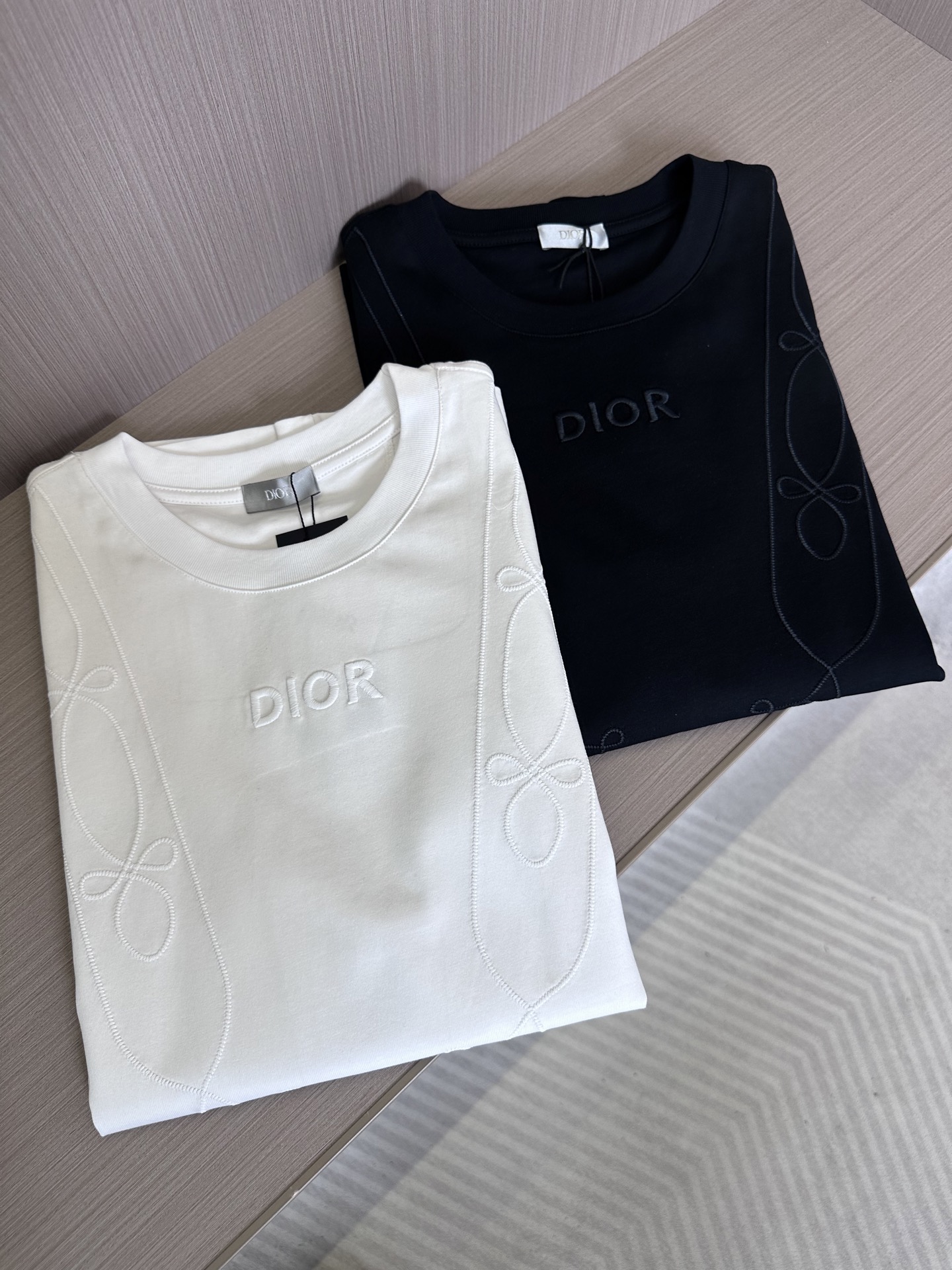 NO:441757,CD25SS spring and summer new jersey cotton solid color round neck short Tee, men and women same three-dimensional line logo embroidered casual pullover short-sleeved T-shirt!  D's new T-shirt has become a clear stream in the fashion industry with its simple yet stylish design!   Its fabric is made of customized jersey cotton, which is not only soft and comfortable in texture, but also has excellent breathability, but also has special processing to make the clothes more durable and easy to care for!  In terms of touch, it gives people a warm feeling of being close to nature, as if the summer breeze blows on your face, bringing a hint of coolness and comfort!  The front design of the T-shirt is particularly unique, with smooth lines and patterns running through it, just like a winding stream in the morning light, adding a bit of agility and vitality to the whole piece of clothing!  At the intersection of this line, there is the brand’s classic letter logo, which quietly tells the brand’s history and inheritance!  The embroidery thread of the same color as the body of the clothes is carefully embroidered through the imported ten thousand needle embroidery process, making the patterns full and three-dimensional, with different shapes, as if they were about to emerge from the clothes. The visual effect is extremely fashionable and unforgettable at a glance!  The basic straight-tube cutting method not only retains the classic elements of the T-shirt, but also takes into account the comfort and versatility of wearing!  Recommended for the same style as men and women!  Black/white, two colors into it!  Size S-XXL S S shoulder width 45cm-bust 102cm-length 68cm M S shoulder width 46cm-bust 106cm-length 70cm L S shoulder width 47cm-bust 110cm-length 72cm XL S shoulder width 48cm-bust 114cm-length 74cm XXL S shoulder width 50cm-bust 118cm-length 76cm Size recommended (standard version) Height 174-140 catties, try on M size appropriately!  A boy can choose S code within 130 catties, a M code for 130-143 catties, a L code for 143-156 catties, a XL code for 156-170 catties, and a XXL code for 170-185 catties!  All girls can choose S code!  ,T-shirt,tees,t-shirt,alexander wang19860909CD25SS春夏新款平纹针织棉布纯色圆领短Tee,男女同款立体线条标识刺绣休闲套头短袖T恤衫！D新款T恤以其简约而不失格调的设计,成为了时尚界的一股清流！  其面料选用客供定制平纹针织棉布,不仅质地柔软舒适,透气性能极佳,而且经过特殊工艺处理,使得衣物更加耐穿且易于打理！在触感上它给人一种亲近自然的温馨感受,仿佛夏日微风拂面,带来一丝丝清凉与惬意！T恤的前幅设计尤为独特,流畅的线条图案贯穿其中,宛如晨曦中蜿蜒的溪流,为整件衣物增添了几分灵动与活力！而在这条线条的交汇处,则是品牌的经典字母标识,它静静地诉说着品牌的历史与传承！采用了与衣身同色的绣线,通过进口万针刺绣工艺精心绣制而成,使得图案饱满立体,形态各异,仿佛要从衣物中跃然而出,视觉效果极为时髦,让人一眼难忘！基础直筒的剪裁方式,既保留了T恤的经典元素,又兼顾了穿着的舒适性与百搭性！男女同款推荐！黑色/白色,两色入！尺码S-XXL S码肩宽45cm-胸围102cm-衣长68cm M码肩宽46cm-胸围106cm-衣长70cm L码肩宽47cm-胸围110cm-衣长72cm XL码肩宽48cm-胸围114cm-衣长74cm XXL码肩宽50cm-胸围118cm-衣长76cm 尺码推荐（标准版型） 身高174-140斤,试穿M码合适！ 男生体重130斤以内选择S码,130-143斤选择M码,143-156斤选择L码,156-170斤选择XL码,170-185斤选择XXL码！ 女生全部选择S码即可！,,T-shirt,tees，t-shirt,alexander wang,Men's clothing