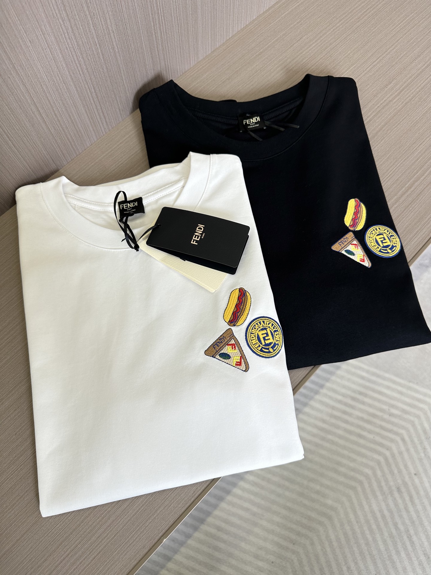 NO:441813,FD25SS spring and summer new jersey cotton round neck short Tee, men and women same color badge embroidered casual straight short-sleeved T-shirt!  F Home's new T-shirt has become a brilliant new star in the fashion industry with its unique fabric selection, exquisite design details and versatile style cutting!  The fabric is selected from customized jersey cotton fabrics for customer supply. It not only has soft and comfortable texture, but also has excellent breathability, but also brings an indescribable tenderness and skin-friendliness to the touch, as if every inch of skin can be taken care of under this gentle wrap!  The colorful burgers and sandwiches on the chest are vividly displayed on the clothes, and they are presented in the form of embroidery. Each stitch and thread reveal the craftsman's exquisite skills and the ultimate pursuit of details!  The back collar is cleverly decorated with double F logos, which inadvertently enhances the fashion sense and recognition of the entire T-shirt!  The basic round neck cut not only retains the classic elements of the T-shirt, but also makes the whole piece of clothing more fitting with the body, showing a casual but stylish beauty!  Black/white, two colors into it!  Size S-XXL S S shoulder width 45cm-bust 102cm-length 68cm M S shoulder width 46cm-bust 106cm-length 70cm L S shoulder width 47cm-bust 110cm-length 72cm XL S shoulder width 48cm-bust 114cm-length 74cm XXL S shoulder width 50cm-bust 118cm-length 76cm Size recommended (standard version) Height 174-140 catties, try on M size appropriately!  A boy can choose S code within 130 catties, a M code for 130-143 catties, a L code for 143-156 catties, a XL code for 156-170 catties, and a XXL code for 170-185 catties!  All girls can choose S code!  ,fendi,T-shirt,tees,t-shirt,alexander wang19860909FD25SS春夏新款平纹针织棉布圆领短Tee,男女同款彩色徽章刺绣休闲直筒短袖T恤衫！F家新款T恤以其独特的面料选择、精妙的设计细节以及百搭的版型裁剪,成为了时尚界的一颗璀璨新星！ 其面料精选自客供定制平纹针织棉布,不仅质地柔软舒适,透气性极佳,更在触感上带来一种难以言喻的温柔与亲肤感,仿佛每一寸肌肤都能在这轻柔的包裹下得到最细致的呵护！胸前色彩斑斓的汉堡与三明治图案跃然衣上,它们以刺绣的形式呈现,每一针每一线都透露着匠人的精湛技艺与对细节的极致追求！后领处巧妙地点缀着双F标识,更在不经意间提升了整件T恤的时尚感与辨识度！基础圆领版型裁剪,既保留了T恤的经典元素,又通过恰到好处的剪裁,使得整件衣物更加贴合身形,展现出一种休闲而不失格调的美感！黑色/白色,两色入！尺码S-XXL S码肩宽45cm-胸围102cm-衣长68cm M码肩宽46cm-胸围106cm-衣长70cm L码肩宽47cm-胸围110cm-衣长72cm XL码肩宽48cm-胸围114cm-衣长74cm XXL码肩宽50cm-胸围118cm-衣长76cm 尺码推荐（标准版型） 身高174-140斤,试穿M码合适！ 男生体重130斤以内选择S码,130-143斤选择M码,143-156斤选择L码,156-170斤选择XL码,170-185斤选择XXL码！ 女生全部选择S码即可！,,fendi,T-shirt,tees，t-shirt,alexander wang,Men's clothing