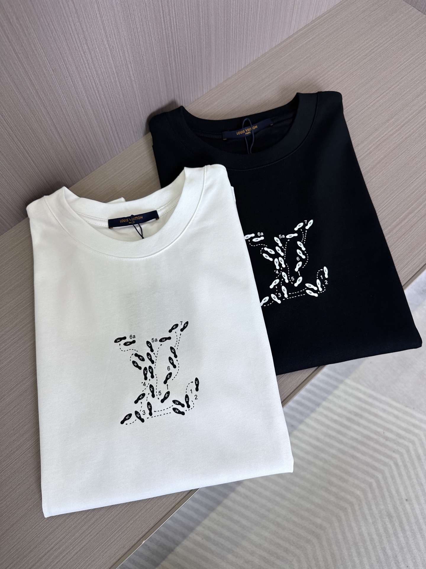 NO:146112,1V25SS spring and summer new jersey cotton round neck short T, men and women same digital footprint logo print casual pullover short-sleeved T-shirt. V home new T-shirt not only strives for excellence in fabric selection, but also unique in design!  The fabric is made of customized jersey cotton, with delicate and soft texture and excellent breathability, giving the wearer the most comfortable experience even in hot summer!  The eye-catching digital footprints on the chest are vividly displayed on the clothes. This is not only a symbol of fashion, but also an innovative interpretation of the brand logo!  The design of the back is also fascinating, and a vivid cartoon character pattern print comes into view, adding a bit of fun and artistic sense to the entire T-shirt!  The iconic mirror flip label breaks the traditional symmetrical aesthetics and presents brand information from a completely new perspective!  The basic straight round neck design is simple and generous, and does not pick on the figure. It can be easily controlled whether it is daily casual or fashionable!  Black/white, two colors into it!  Size S-XXL S S shoulder width 45cm-bust 104cm-length 68cm M S shoulder width 46cm-bust 108cm-length 70cm L S shoulder width 47cm-bust 112cm-length 72cm XL S shoulder width 48cm-bust 116cm-length 74cm XXL S shoulder width 49cm-bust 120cm-length 76cm Size recommendation (standard version) Height 174-140 catties, try on M size appropriately!  A boy can choose S code within 132 catties, a M code for 132-144 catties, a L code for 144-156 catties, a XL code for 156-170 catties, and a XXL code for 170-185 catties!  All girls can choose S code!  ,T-shirt,tees,t-shirt,alexander wang198609091V25SS春夏新款平纹针织棉布圆领短T,男女同款数字脚印标识印花休闲套头短袖T恤衫 V家新款T恤不仅在面料选择上精益求精,在设计上更是独具匠心！ 其面料采用的是客供定制的平纹针织棉布,质地细腻柔软,透气性能极佳,即使在炎炎夏日也能给予穿着者最舒适的体验！胸前位置醒目的数字脚印图案跃然衣上,这不仅是时尚的象征,更是品牌标识Logo的一种创新演绎！而后幅的设计同样引人入胜,一幅生动的漫画人物图案印花映入眼帘,为整件T恤增添了几分趣味性和艺术感！标志性的镜像翻转标签,打破了传统的对称美学,以一种全新的视角呈现品牌信息！基础直筒圆领设计,简洁大方,不挑身材,无论是日常休闲还是时尚搭配都能轻松驾驭！黑色/白色,两色入！尺码S-XXL S码肩宽45cm-胸围104cm-衣长68cm M码肩宽46cm-胸围108cm-衣长70cm L码肩宽47cm-胸围112cm-衣长72cm XL码肩宽48cm-胸围116cm-衣长74cm XXL码肩宽49cm-胸围120cm-衣长76cm 尺码推荐（标准版型） 身高174-140斤,试穿M码合适！ 男生体重132斤以内选择S码,132-144斤选择M码,144-156斤选择L码,156-170斤选择XL码,170-185斤选择XXL码！ 女生全部选择S码即可！,,T-shirt,tees，t-shirt,alexander wang,Men's clothing