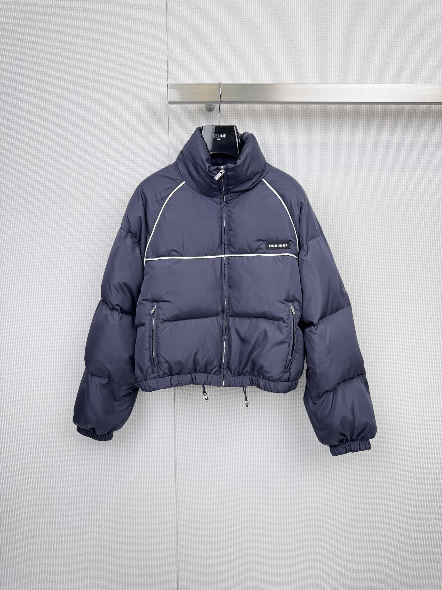 NO:589579,Comes with dust bag MIUMIU2025 new bread down jacket, the perfect balance of winter fashion and warmth, stand-up collar design, neat silhouette, dark blue background with white lines, simple yet high-end, stand-up collar cut to prevent wind  It keeps warm, and the fluffy down filling locks in temperature without looking bulky. The metal zipper and side pocket details add a sense of functionality, and the details are textured. It is both practical and aesthetic. The drawstring at the hem can be freely adjusted to prevent cold wind from entering; two-way pull  The chain is smooth and wear-resistant, and the invisible pockets on both sides are designed for both storage and overall smooth lines. The iconic low-key logo is embellished to highlight the brand identity in a low-key manner. It can be worn in many ways and can be easily controlled in various scenes. It is suitable for commuting, dating, and outdoor leisure. The dark blue color is versatile and does not matter skin color. Whether it is paired with jeans or a skirt, it can instantly enhance the layering of winter wear. Size SML,,miumiu,skirts,jeans,down  jacket,alexander wang19860909配防尘袋MIUMIU2025新款面包羽绒服,冬日时髦与温暖的完美平衡,立领设计,廓形利落,深蓝底色搭配白色线条,简约中透出高级感,立领剪裁防风保暖,蓬松充绒量锁住温度却不显臃肿,金属拉链与侧边口袋细节增添机能感,细节见质感,实用与美学兼具,下摆抽绳可自由调节松紧,防止冷风灌入；双向拉链顺滑耐磨,两侧隐形口袋设计兼顾收纳与整体流畅线条,标志性低调logo点缀,低调彰显品牌身份,一衣多穿,轻松驾驭多种场景,通勤、约会、户外休闲皆宜,深蓝色系百搭不挑肤色,无论是搭配牛仔裤还是半裙都能瞬间提升冬日穿搭层次感.码数SML,,miumiu,skirts,jeans,down jacket,alexander wang,Women's clothing