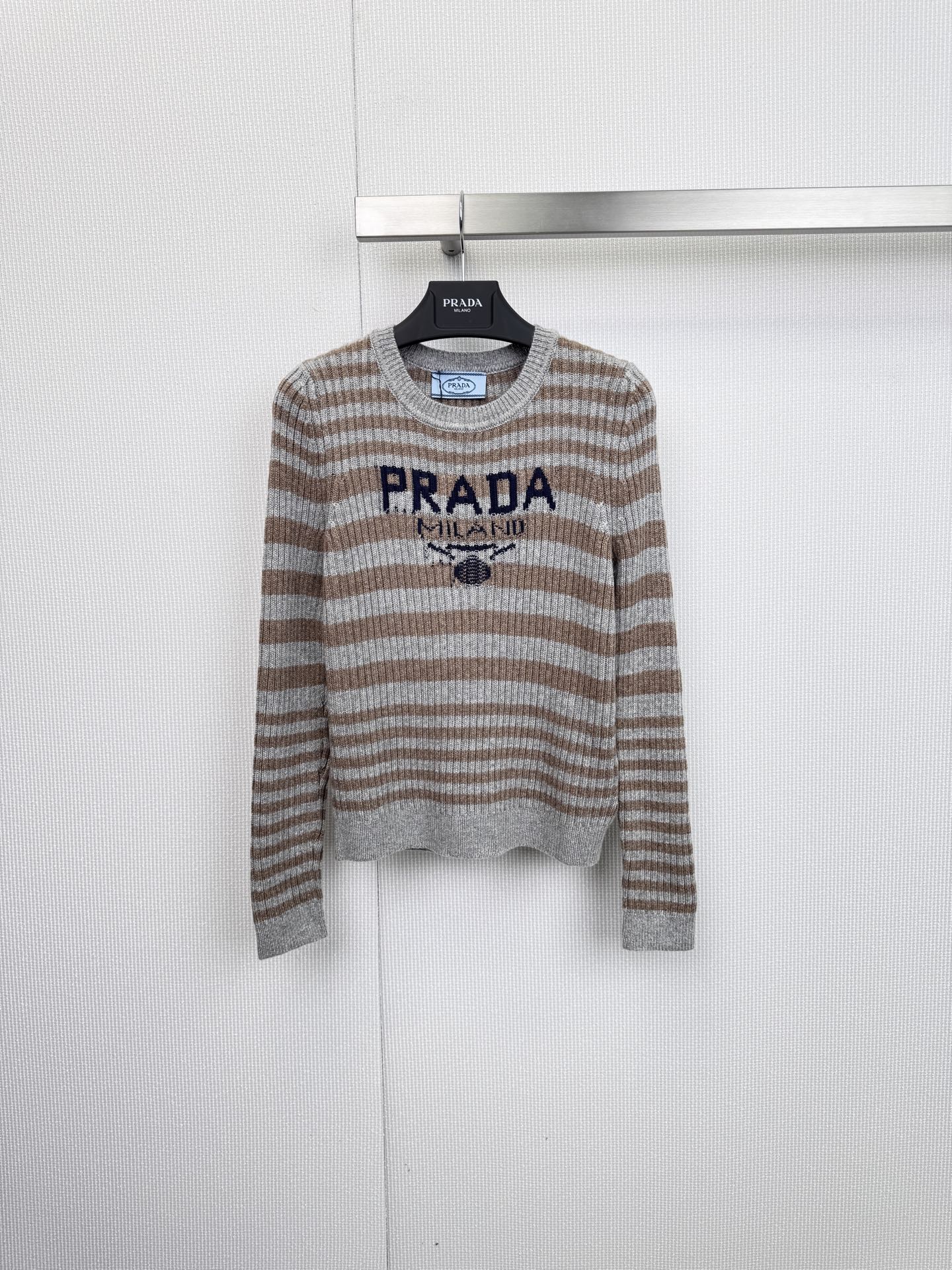 NO:627774,PRADA's classic striped sweater is made of high-quality blended fabrics in Italy. It combines the brand's iconic logo print with a simple and comfortable fit to create a daily essential item with both casual texture and luxurious style. The sweater adopts a classic black and white or gray and brown wide stripe design. The color is calm and highly recognizable, which can easily enhance the sense of layering. The chest is eye-catchingly decorated with 'PRADA' in red or dark blue.  'MILANO' embroidered/printed badge instantly lights up the overall look and highlights the extraordinary taste. The round neck design is matched with rib knitted cuffs and hem to ensure comfort and a neat silhouette. The solid color splicing used in the collar, cuffs, etc. adds to the design ingenuity. The ingredients are 45 wool, 35 acrylic, and 20 nylon. This golden ratio retains the warmth and high-quality quality of wool.  It combines the softness of acrylic and the wear resistance of nylon to achieve the perfect balance of comfort and durability. Whether it is paired with casual trousers to create a simple and comfortable weekend trip look, or layered with a suit jacket to inject a touch of casual elegance into a commuting look, this sweater is an indispensable fashion tool. Size SML, prada, jackets  & coats,sweaters,business suit,gold,alexander wang19860909PRADA经典条纹毛衣,以优质混纺面料于意大利精制而成,将品牌标志性的徽标印花与简约舒适的版型相结合,打造出兼具休闲质感与奢华格调的日常必备单品,毛衣采用经典的黑白或灰棕宽条纹设计,色调沉稳且极具辨识度,轻松提升穿搭层次感,胸前醒目地装饰着红色或深蓝色的“PRADA MILANO”刺绣/印花徽章,瞬间点亮整体造型,彰显不凡品味,圆领设计搭配罗纹针织的袖口与下摆,确保了穿着的舒适性与利落廓形.领口、袖口等处采用的纯色拼接,更添设计巧思,成分为45羊毛、35腈纶、20尼龙,这一黄金配比既保留了羊毛的保暖性与高级质感,又融入了腈纶的柔软与尼龙的耐磨性,实现了舒适度与耐用性的完美平衡,无论是搭配休闲裤装打造简约舒适的周末出行look,还是与西装外套层叠穿搭,为通勤造型注入一丝随性的优雅,这款毛衣都是不可或缺的时尚利器.码数SML,,prada,jackets & coats,sweaters,business suit,gold,alexander wang,Women's clothing