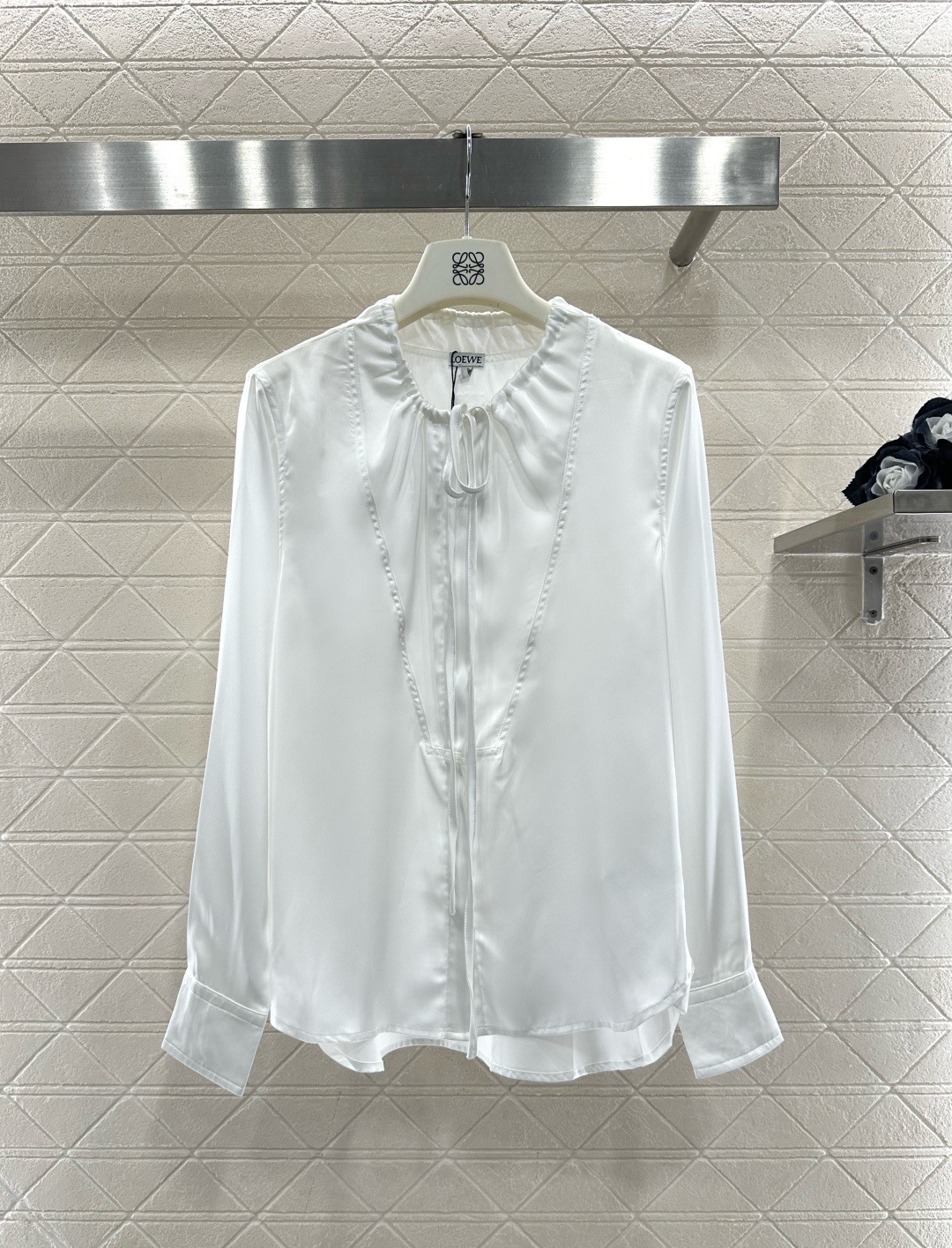 NO:697482,Loewe white satin lace shirt, this white lace shirt is made of high-quality satin, smooth and delicate to the touch, full of luster, French lace design + tie neckline, elegant and gentle, very suitable for spring and autumn, the lining design improves comfort and avoids embarrassment of light transmission. Whether commuting, dating or daily outings, it looks great with skirts or high-waisted pants, easily creating a Korean atmosphere or French elegance!  Size SML,,loewe,skirts,shirts,19860909Loewe白色缎面花边衬衫,这款白色花边衬衫,采用高品质缎面,触感柔滑细腻,光泽感满满,法式花边设计+系带领口,优雅又温柔,春秋季节穿超合适,内衬设计提升舒适度,避免透光尴尬,无论通勤、约会还是日常出街,搭配裙装或高腰裤都很出彩,轻松打造韩系氛围感或法式优雅风！码数SML,,loewe,skirts,shirts,,Women's clothing