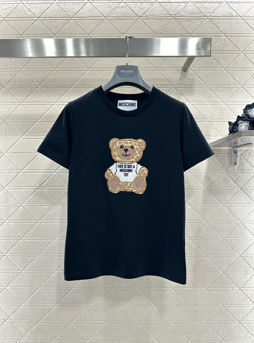 NO:709692,MOSCHINO bear embroidered short-sleeved T-shirt, this black pure cotton T-shirt, the bear embroidery on the front is very recognizable, with exquisite details and full of fun. The bear wears a white T-shirt with 'This is not a MOSCHINO toy' printed on it. It directly expresses the brand's attitude. It has a round neck design and a loose fit. It can be easily worn in daily casual or street style. It goes well with jeans and short skirts and is full of youthful vitality!  Size SML,,skirts,jeans,T-shirt,tees,t-shirt,19860909MOSCHINO小熊刺绣短袖T恤,这款黑色纯棉T恤,正面小熊刺绣超有辨识度,细节精致,趣味满满,小熊穿白T,印有“This is not a MOSCHINO toy”,品牌态度直接拉满,圆领设计,宽松版型,日常休闲或街头风都能轻松驾驭,搭配牛仔裤、短裙都很出彩,青春活力感十足！码数SML,,skirts,jeans,T-shirt,tees，t-shirt,,Women's clothing