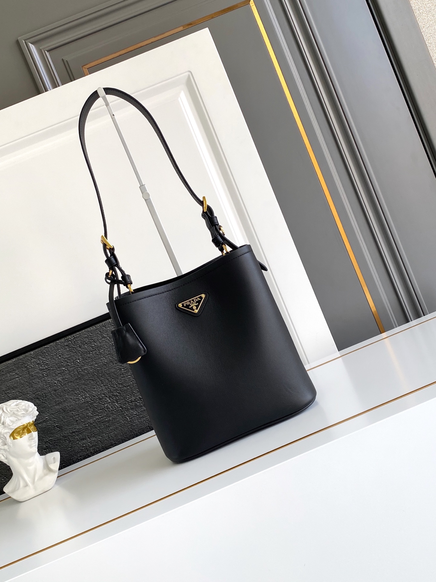 Prada 这款皮革手袋拥有柔和线条与精美设计，凸显 格调与手工细节。实用百搭，饰有涂珐琅三角形金属徽标，增添辨识度