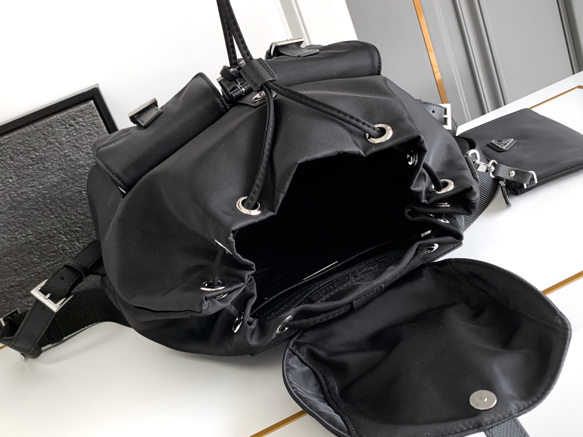 Prada 这款尼龙双肩包采用 Saffiano皮革饰边 融合多种材质 并饰有三角形徽标