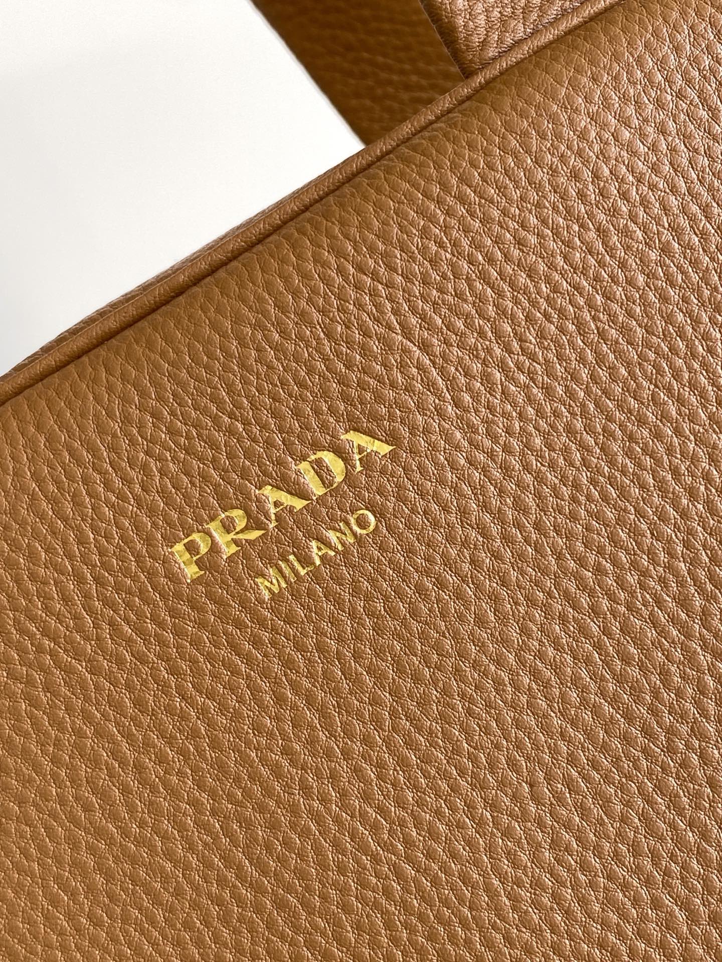 Prada 这款天然粒面皮革制成的顶部提手包袋以柔软的轮廓进行了重新诠释 可手提或搭配可拆式肩带佩戴
