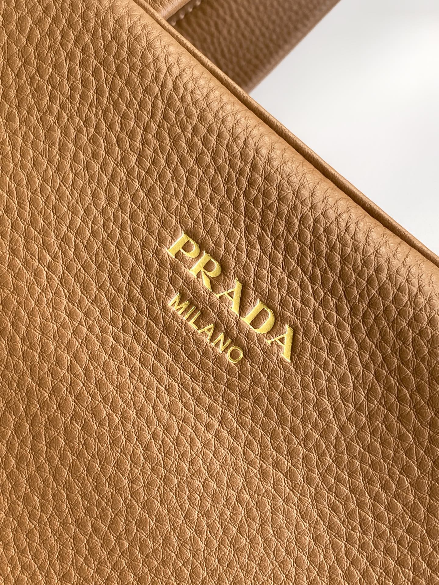 Prada 这款天然粒面皮革制成的顶部提手包袋以柔软的轮廓进行了重新诠释 可手提或搭配可拆式肩带佩戴