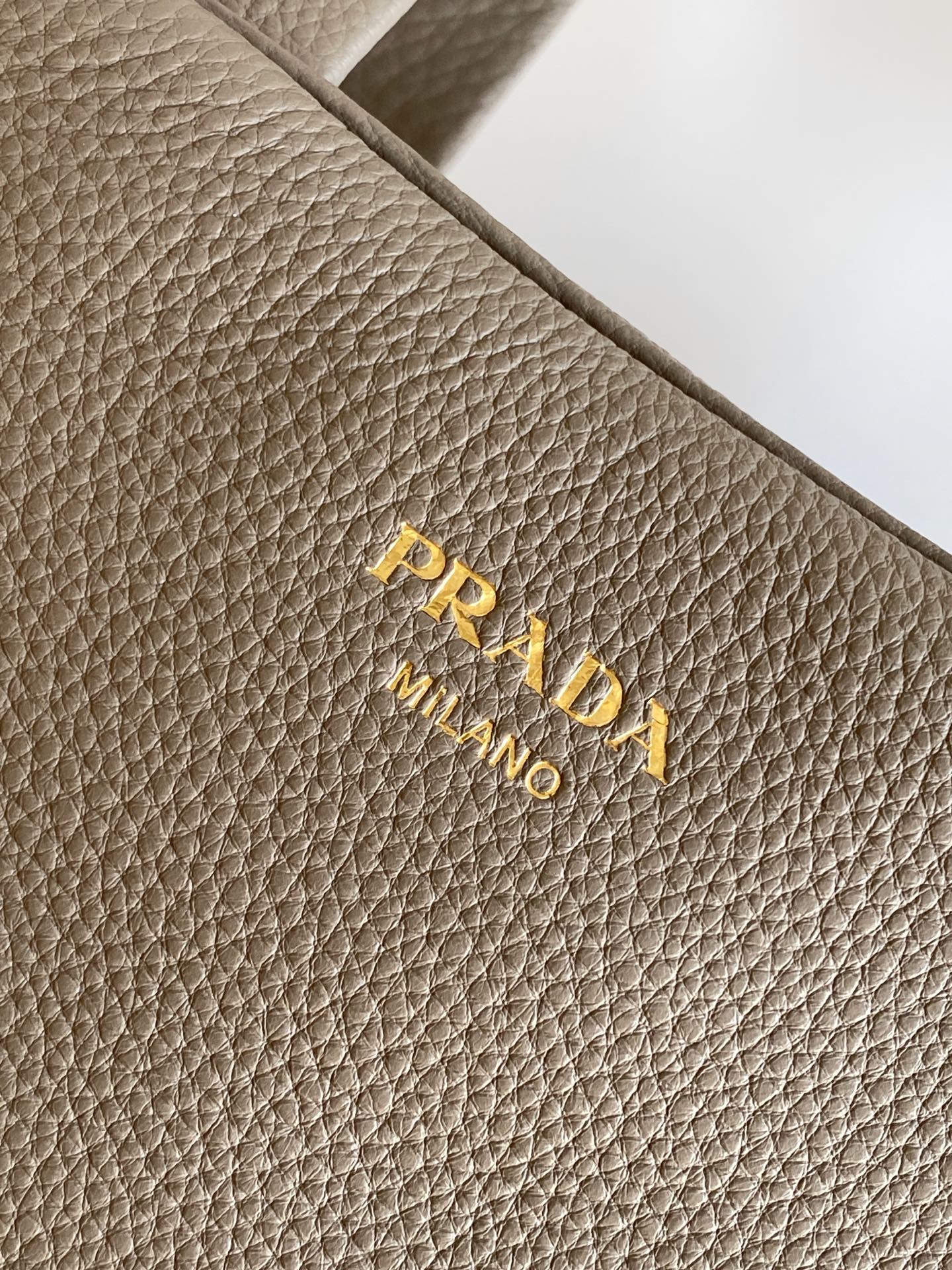 Prada 这款天然粒面皮革制成的顶部提手包袋以柔软的轮廓进行了重新诠释 可手提或搭配可拆式肩带佩戴