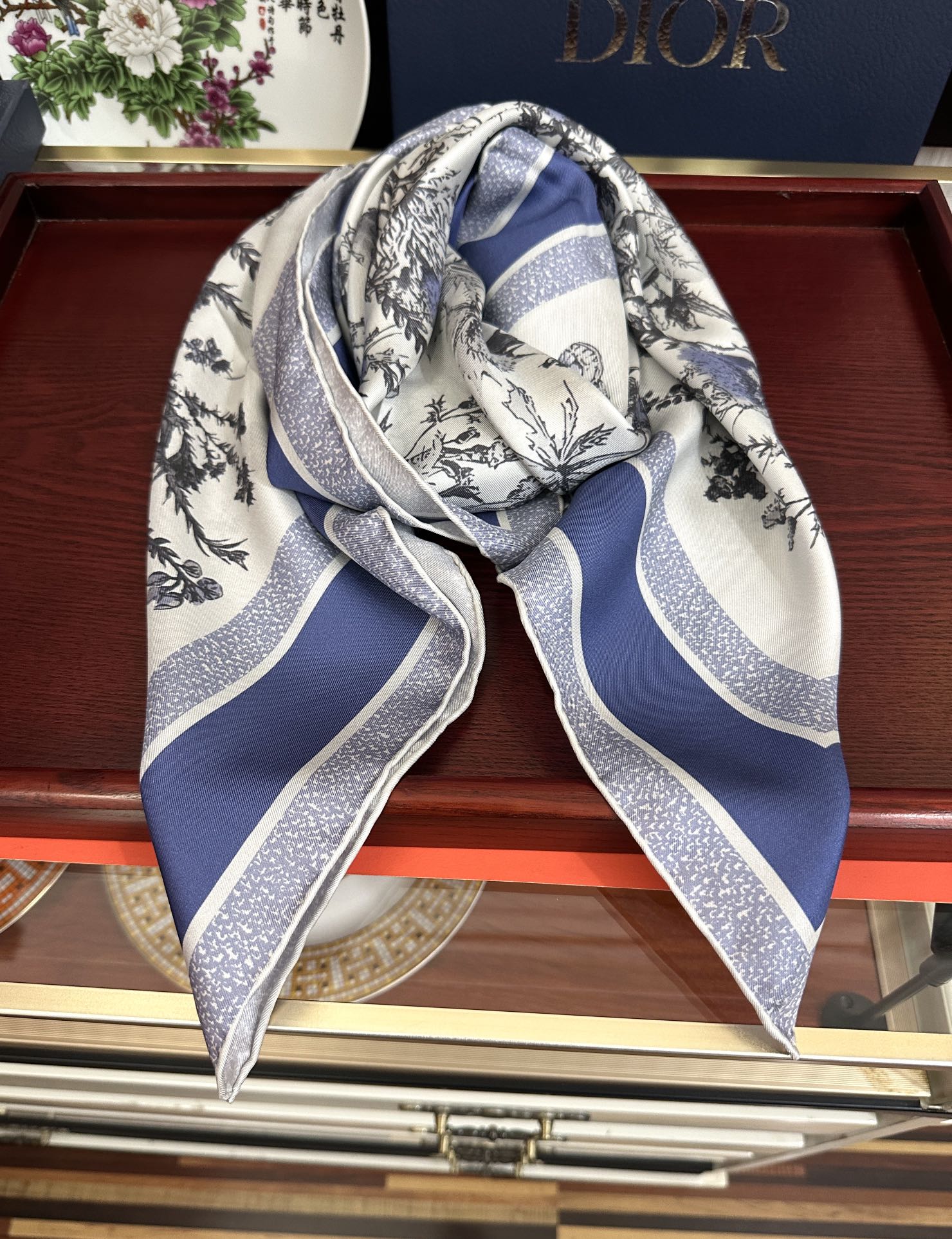Dior 高版本Dior Chardons 图案印花 展示象征着保护、韧性和自由的苏格兰国花 采用白色和蓝色桑蚕丝斜纹面料精心制作 双面设计搭配手工卷边 点缀以对比鲜明的 Christian 标志提花条形图案提升格调 可系在颈部或作为头巾使用 打造 的 造型