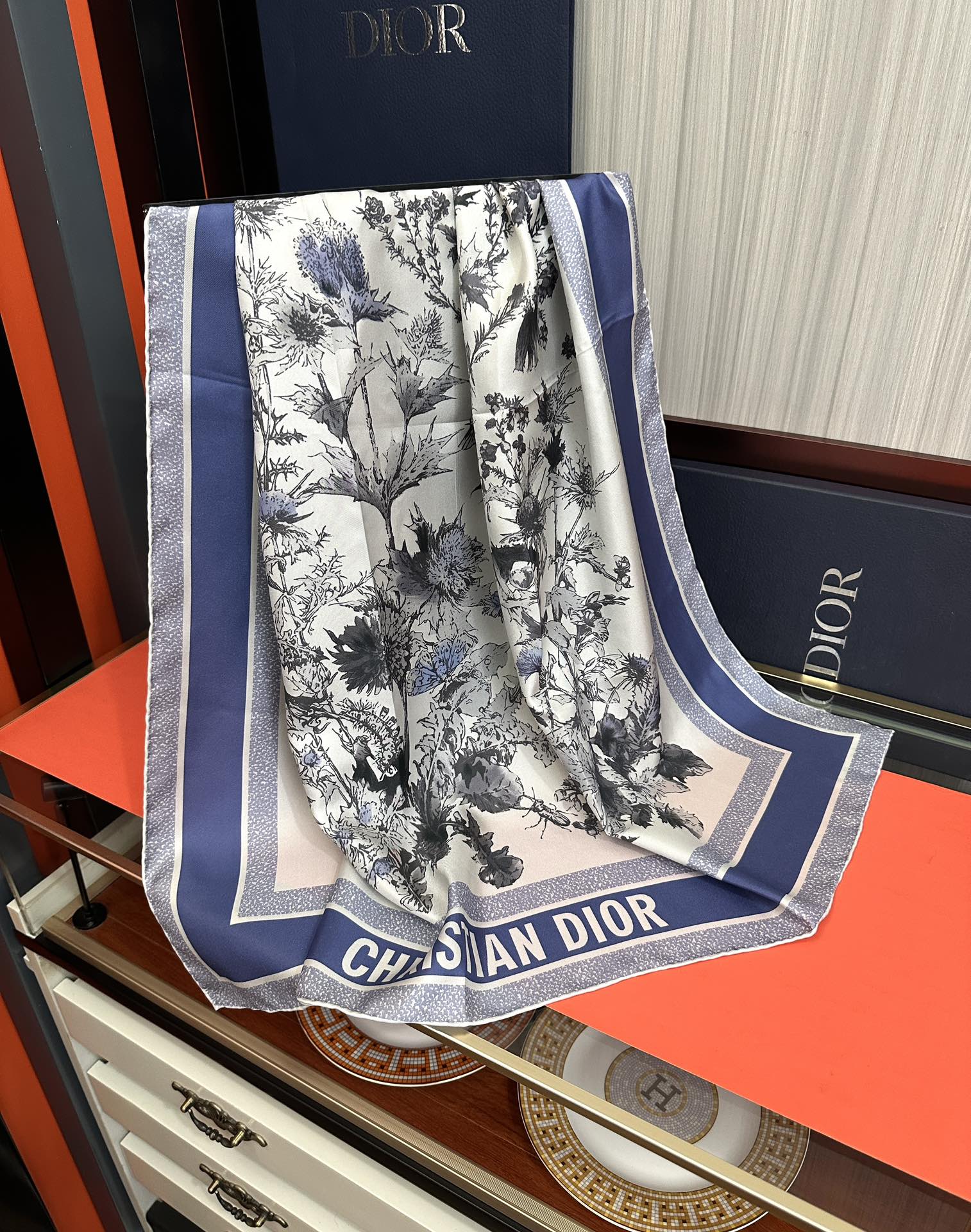 Dior 高版本Dior Chardons 图案印花 展示象征着保护、韧性和自由的苏格兰国花 采用白色和蓝色桑蚕丝斜纹面料精心制作 双面设计搭配手工卷边 点缀以对比鲜明的 Christian 标志提花条形图案提升格调 可系在颈部或作为头巾使用 打造 的 造型