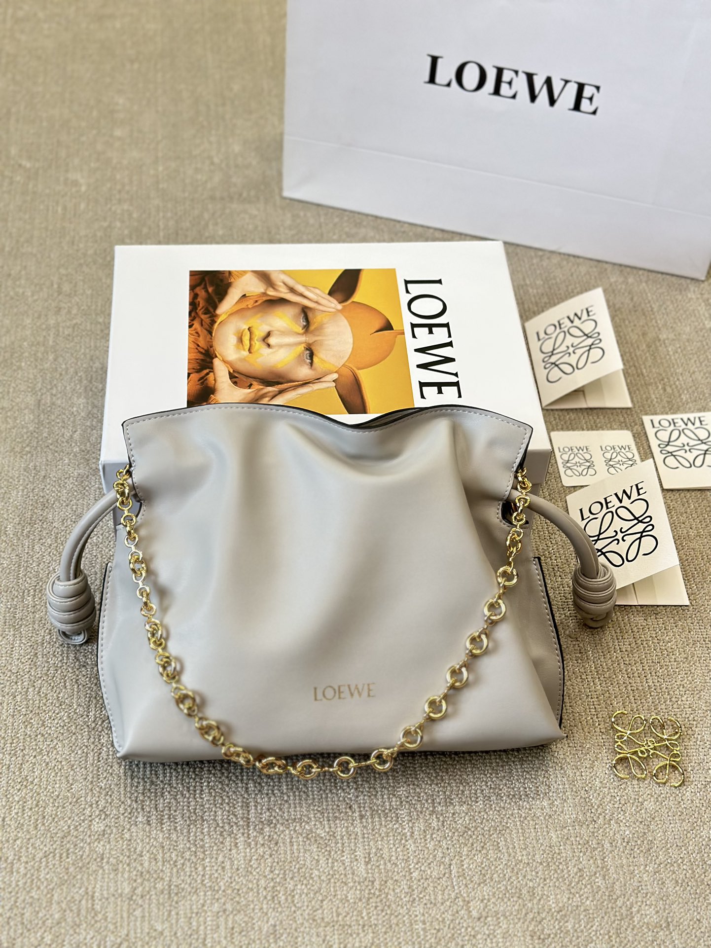 牛皮版本 p210
Loewe 迷你羊皮 purse 福袋 
Loewe 兴 迷你柔软纳帕羊皮革 Flamenco Purse 福袋
采用褶皱设计，侧面搭配标志性绳结等关键细节。款式
时尚百搭，可作为手拿包携带，亦可搭配甜甜圈链条肩背，或搭配皮革肩带斜挎。此版本采用柔软纳帕羊皮革制成。可肩背、斜挎或手提*可拆卸可调节皮革肩带*可
拆卸甜甜圈链条饰*Anagram 镌刻卵石纹*低调的磁扣开
合*绒面革衬里烫金或烫银*(配套金屬鏈條加长皮肩帶）尺寸30 25cm