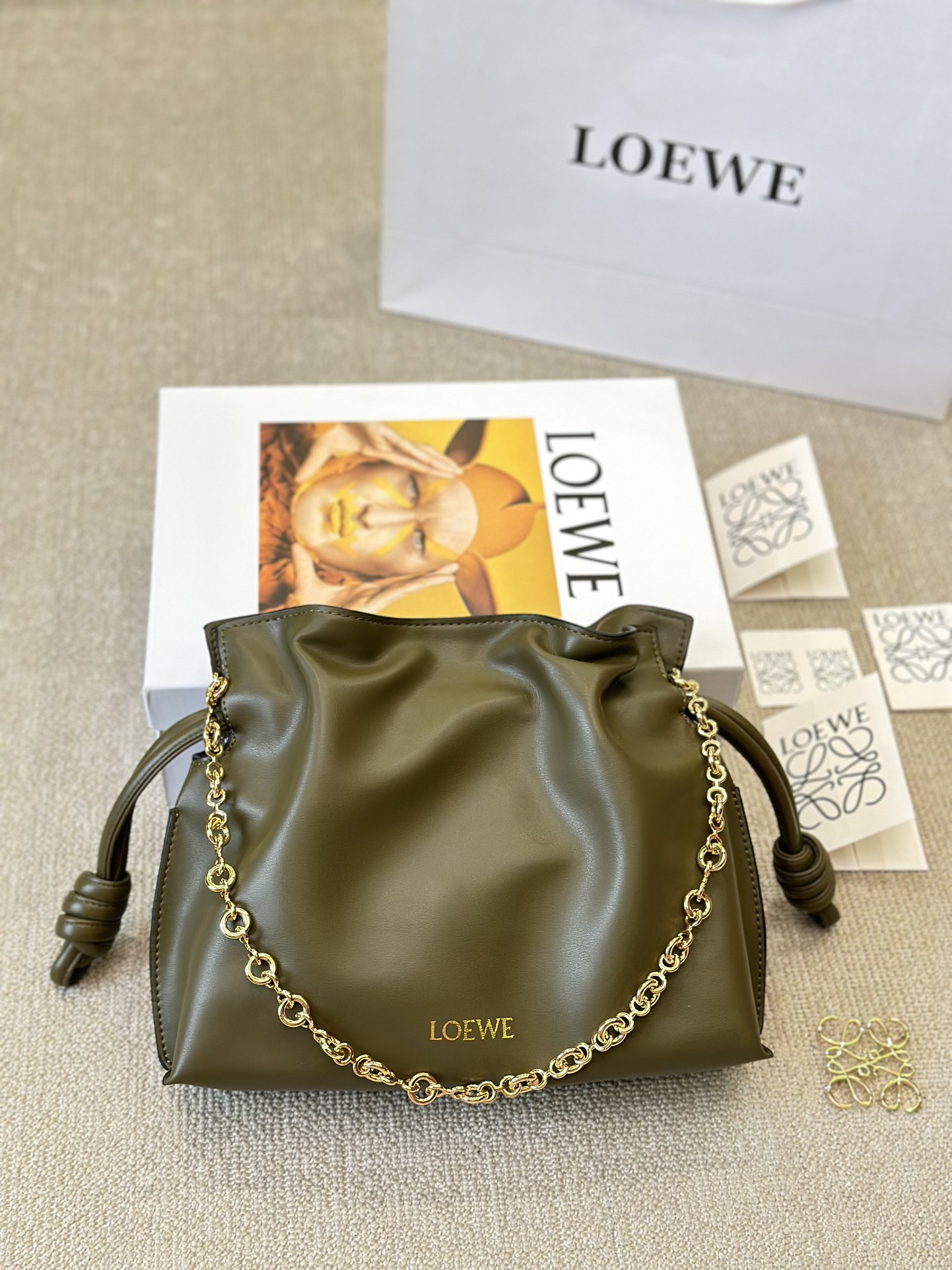 牛皮版本 p210
Loewe 迷你羊皮 purse 福袋 
Loewe 兴 迷你柔软纳帕羊皮革 Flamenco Purse 福袋
采用褶皱设计，侧面搭配标志性绳结等关键细节。款式
时尚百搭，可作为手拿包携带，亦可搭配甜甜圈链条肩背，或搭配皮革肩带斜挎。此版本采用柔软纳帕羊皮革制成。可肩背、斜挎或手提*可拆卸可调节皮革肩带*可
拆卸甜甜圈链条饰*Anagram 镌刻卵石纹*低调的磁扣开
合*绒面革衬里烫金或烫银*(配套金屬鏈條加长皮肩帶）尺寸30 25cm
