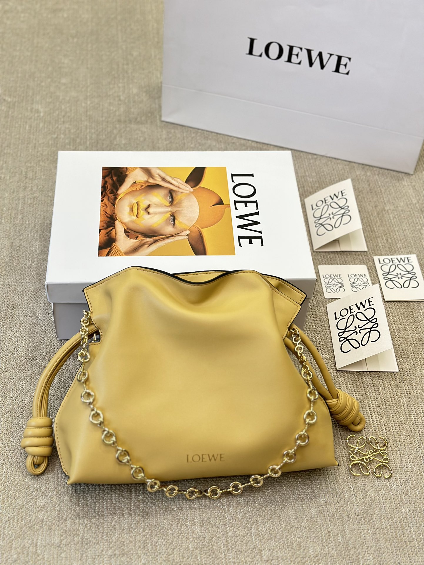 牛皮版本 p210
Loewe 迷你羊皮 purse 福袋 
Loewe 兴 迷你柔软纳帕羊皮革 Flamenco Purse 福袋
采用褶皱设计，侧面搭配标志性绳结等关键细节。款式
时尚百搭，可作为手拿包携带，亦可搭配甜甜圈链条肩背，或搭配皮革肩带斜挎。此版本采用柔软纳帕羊皮革制成。可肩背、斜挎或手提*可拆卸可调节皮革肩带*可
拆卸甜甜圈链条饰*Anagram 镌刻卵石纹*低调的磁扣开
合*绒面革衬里烫金或烫银*(配套金屬鏈條加长皮肩帶）尺寸30 25cm