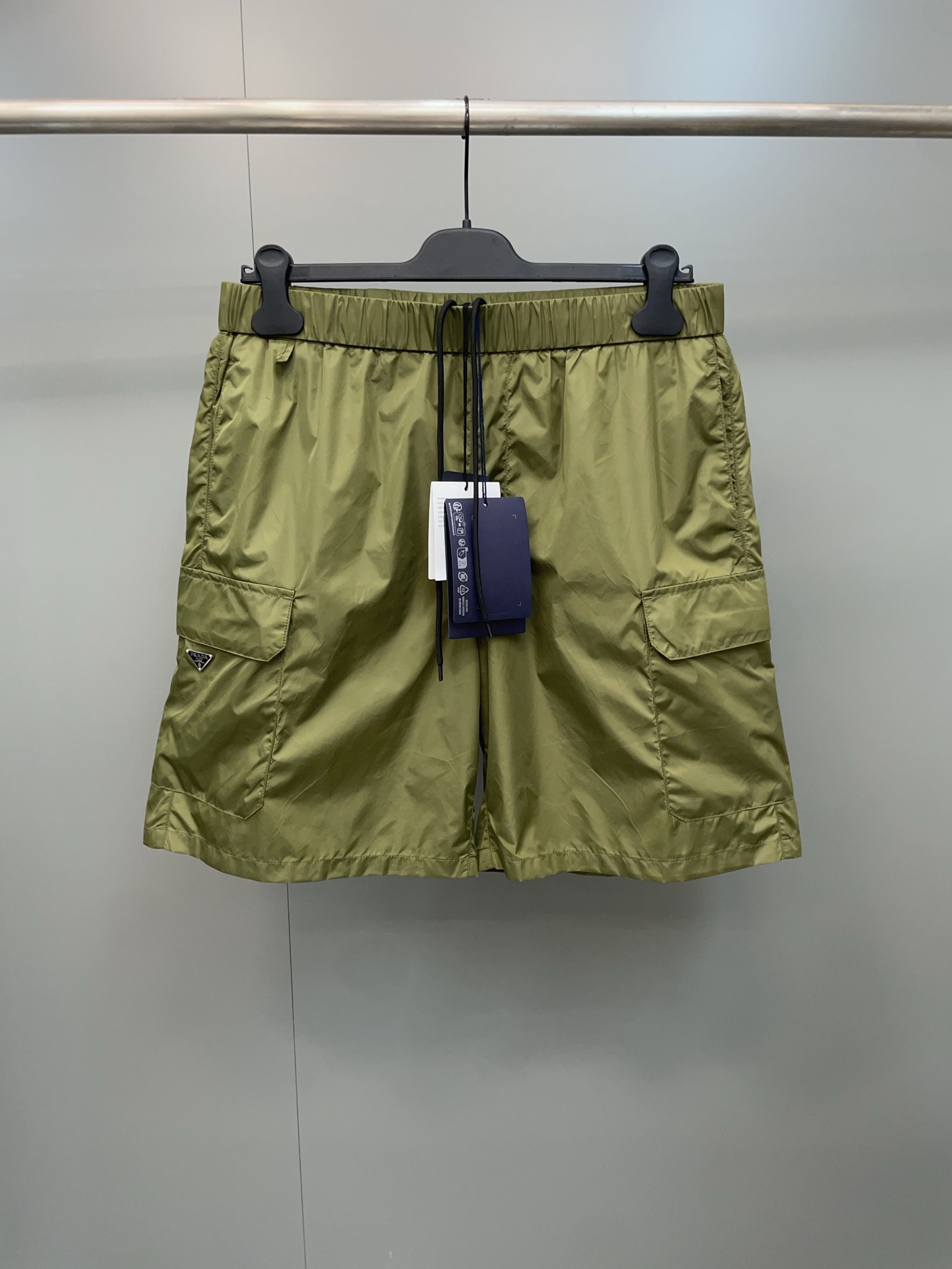 NO:822794,P*ada 26ss new triangle logo work nylon shorts are made of the same regenerated nylon material as the counters. They are lightweight, breathable, quick-drying and anti-wrinkle. They have a matte high-end texture and are not easily deformed after long-term wear.  The classic metal triangle logo on the left pocket is engraved, and the hardware texture is full, which is the core detail of brand recognition. The original three-dimensional pocket cut is restored, taking into account practicality and design, and the details are neatly routed, no different from the original. Size S-XL, Prada-clothing, prada, shorts,19860909P*ada 26ss新款三角标工装尼龙短裤,采用和专柜一致的再生尼龙材质,轻量透气、速干抗皱,自带哑光高级质感,久穿不易变形 左口袋复刻经典金属三角标,五金质感拉满,是品牌辨识度的核心细节.还原原版立体口袋剪裁,兼顾实用性与设计感,细节走线工整,和原版无差.S-XL码,普拉达-服装,prada,shorts,,Women's clothing