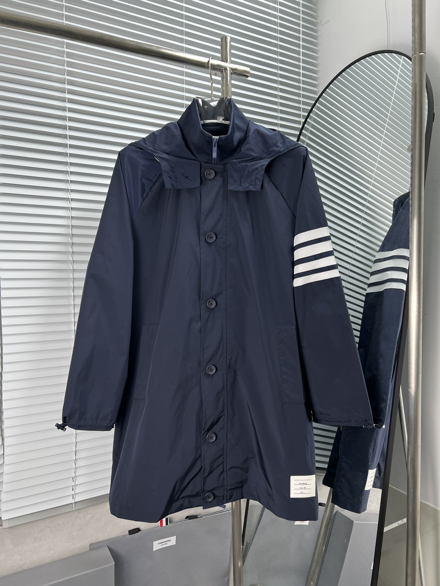 THOM BROWNE🇳🇱长款连帽风衣外套 秋冬长款连帽风衣外套，经典四杠条纹设计，面料柔软亲肤。传承TB出位的剪裁，手臂采用四条白色杆设计，防水面料，同时也让休闲随意的外套多了些高级感和超酷的风格。 颜色：藏青、军绿色 码数：1-4码