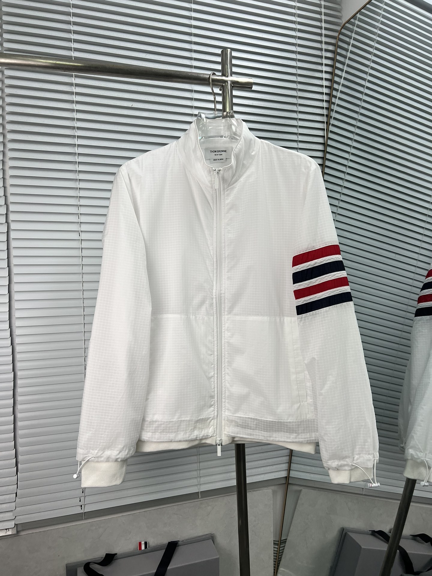 THOM BROWNE2024最新款春夏（双层）梭织拼接针织立领夹克 定制暗格纹尼龙 内里拼接针织面料，二层工艺，透气性，柔软性很赞；门襟拉链设计，袖子经典四条纹搭配 衣角拉伸设计 口袋插兜拉链设计 风格突出有重点 内里针织全包 袖口下摆…