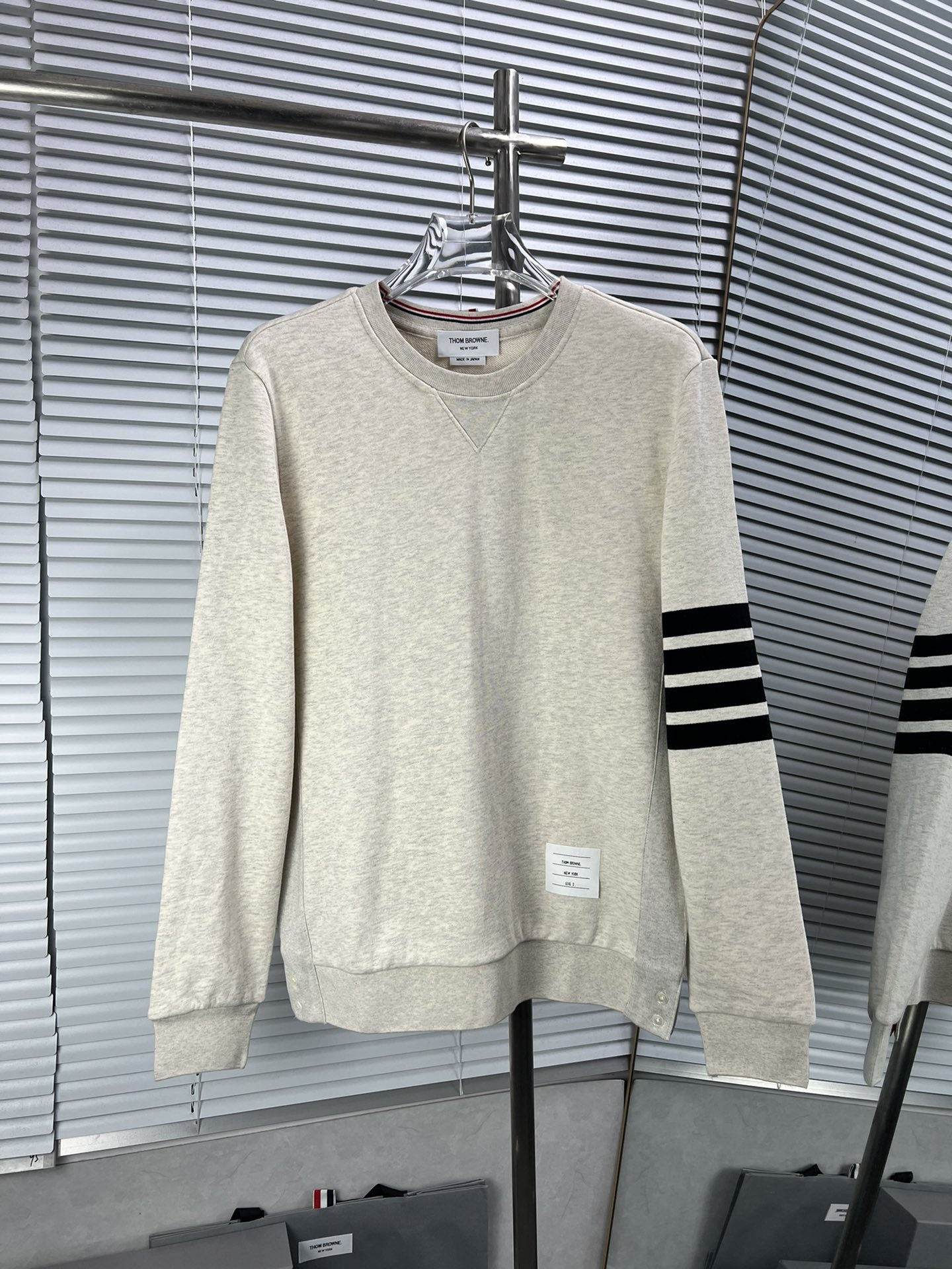 THOM BROWNE clásica sudadera de cuello redondo de cuatro rayas en gris arena. La sudadera de cuello redondo clásica ya …
