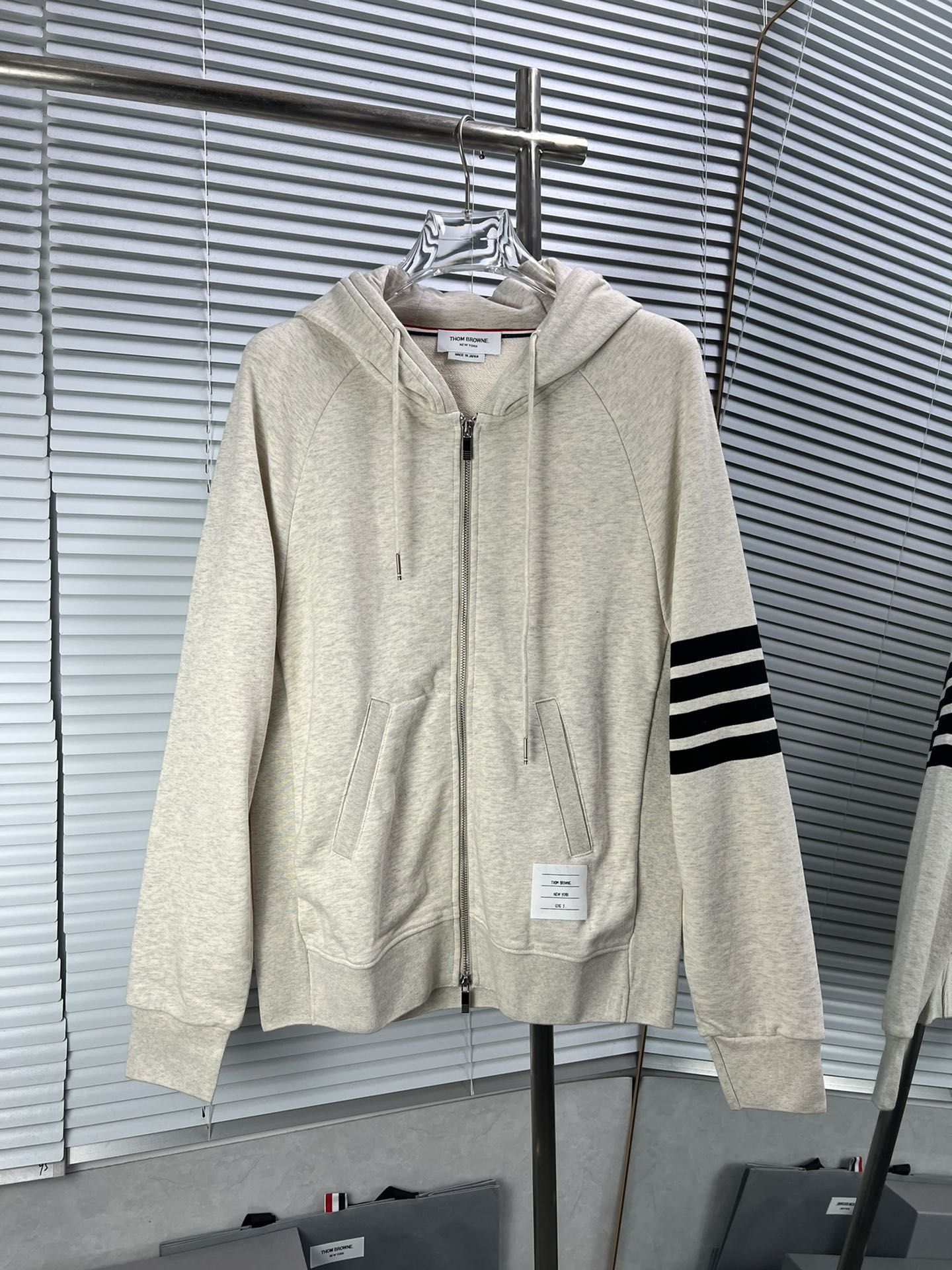 THOM BROWNE clásica sudadera con capucha y cremallera de cuatro rayas en gris arena. Tela de algodón puro de 420 gramos…