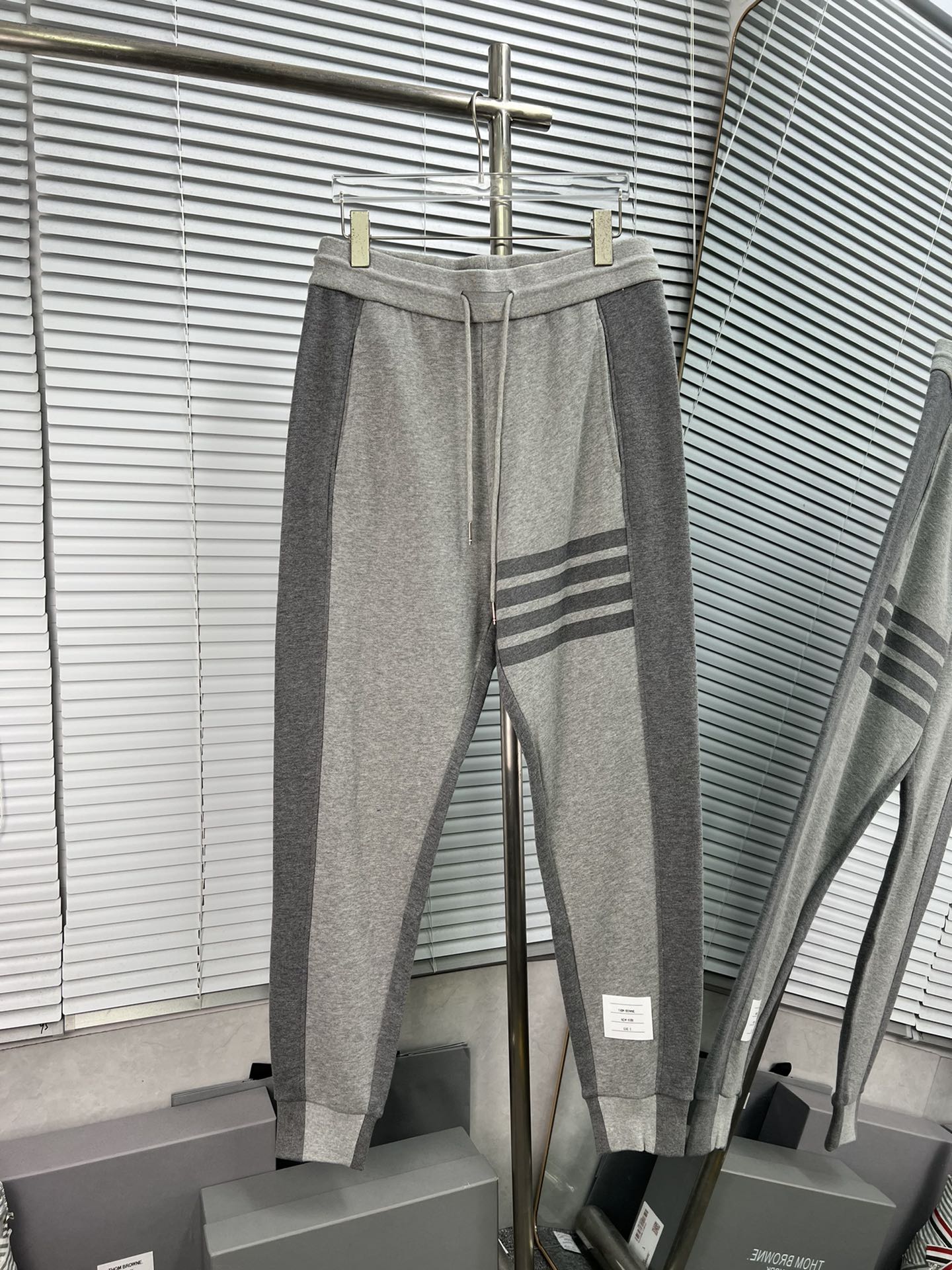 Pantalones largos de THOM BROWNE con rayas laterales grises y cuatro barras, disponibles. Pantalones largos de tejido c…