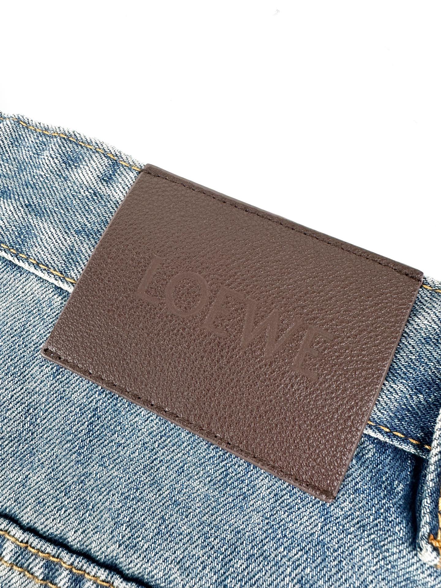 Loewe 定制靛蓝云纹高密丹宁 紧实挺括 细腻柔韧 以雾感水洗靛蓝为基调 自带时光沉淀的高级质感 标志性Anagram镂空印记镌刻后袋 是隐于细节的匠心落款 腰头深棕皮牌压印LOEWE标识 为丹宁缀以矜贵勋章 低调却锋芒暗藏 走线勾勒利落版型 于静谧处流露矜贵质感 自在随性间尽显高阶品味