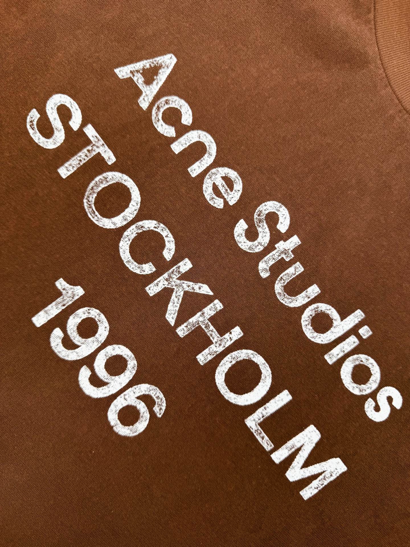 Acne Studios 定制云绒爽滑雪感棉 垂感爽滑 细腻透气 一抹赤陶棕咖悄然绽放 松弛疏离 奢感自生 Acne Studios 1996徽标图案点缀于胸前 字母笔触的深浅不均 宛如岁月镌刻的印记 加以喷绘做旧的不完美感为升华 形成柔与刚的视觉碰撞 无需多言 设计自会说话 让衣服成为穿者个性的延伸