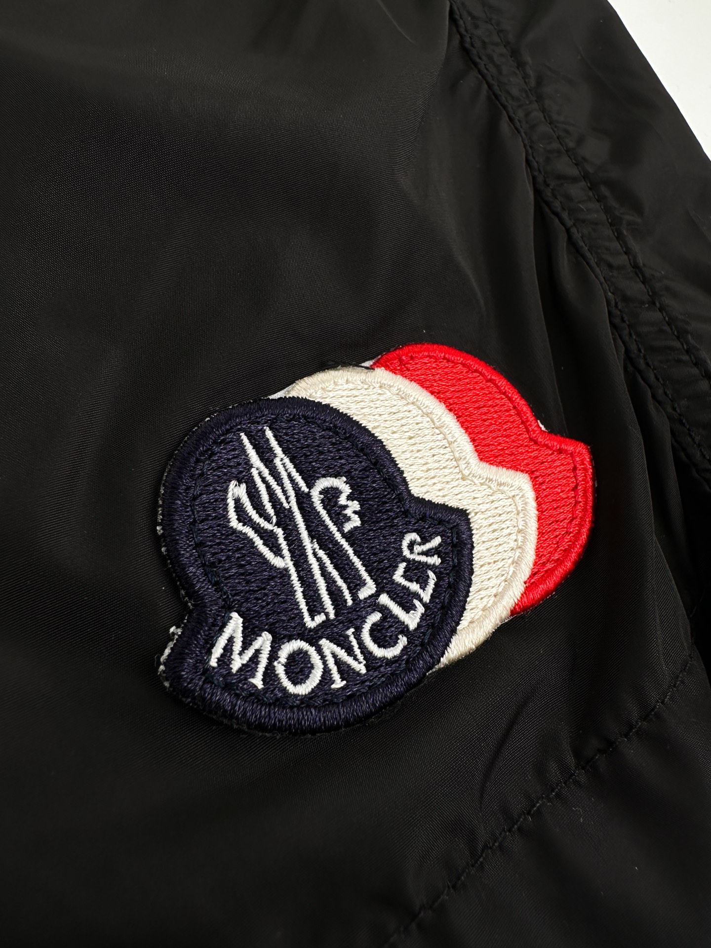 Moncler 定制冰壤棱织尼龙 搭配细密网布衬里 清爽透气 舒适贴肤 以深邃的黑为主色调 纯粹而深邃 标志性Moncler标识贴片轻缀裤身 瞬间为整体造型注入灵魂 彰显品牌魅力 背面巧妙融入拉链口袋 辅以三色饰边点缀 增添层次与动感 每一处细节都是对传统工装的反叛 以轻盈之姿解锁夏日百变奢雅