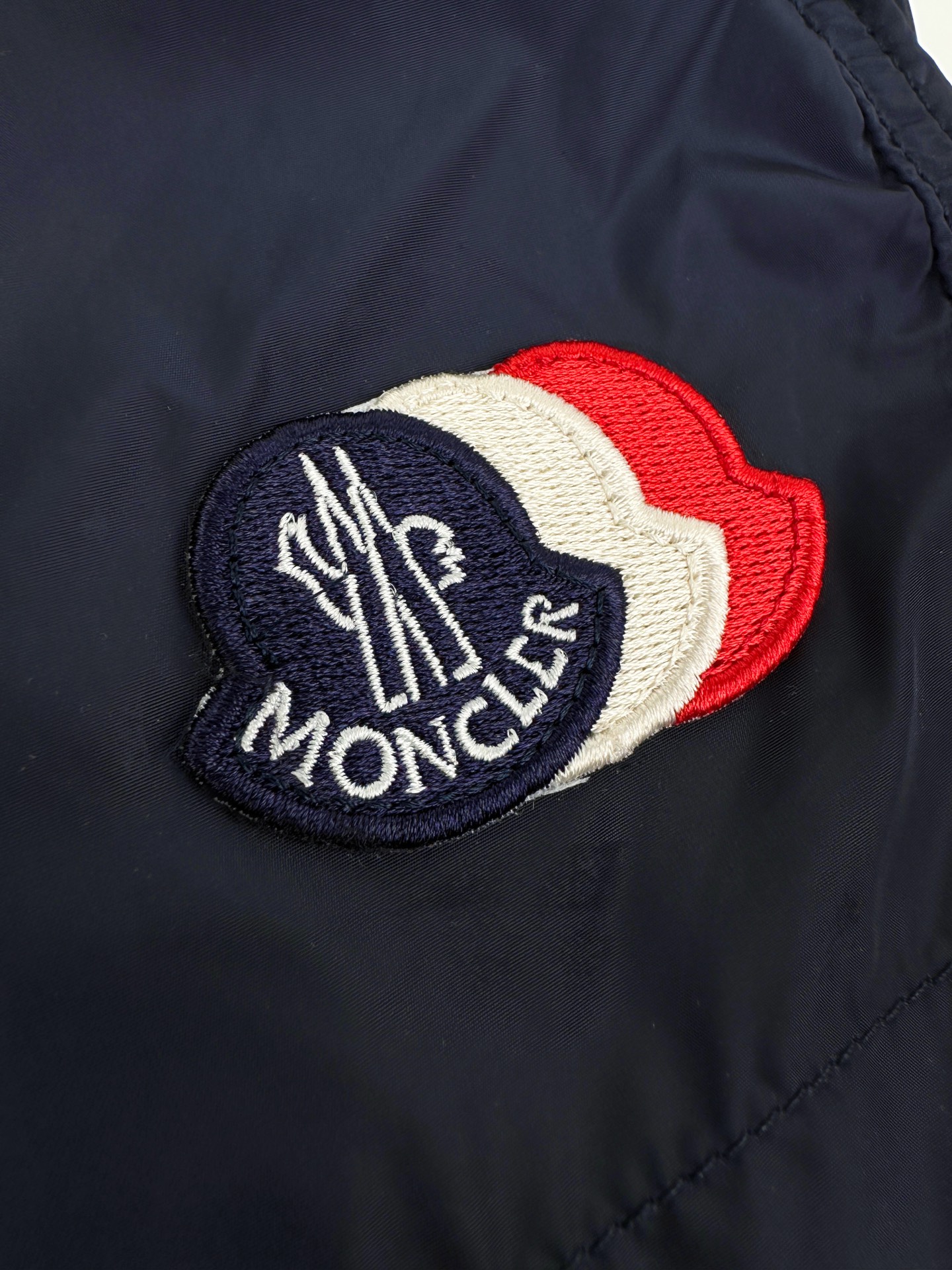 Moncler 定制冰壤棱织尼龙 搭配细密网布衬里 清爽透气 舒适贴肤 以墨海藏蓝为主色调 深邃而沉静 标志性Moncler标识贴片轻缀裤身 瞬间为整体造型注入灵魂 彰显品牌魅力 背面巧妙融入拉链口袋 辅以三色饰边点缀 增添层次与动感 每一处细节都是对传统工装的反叛 以轻盈之姿解锁夏日百变奢雅