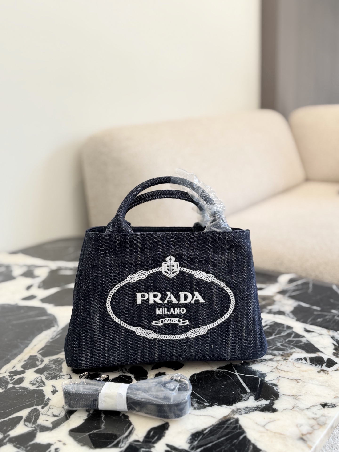P240 | Prada Denim Washed Denim Beach Bag | Prada Denim Beach Bag, Made Of Wear-resistant Denim Material With White Embroidered Logo, Simple And Recognizable. Small Bag Shape, Bottom Length Is About 28cm, Moderate Capacity, Suitable For Commuting Or Going Out On The Street Hand-held + Detachable Shoulder Strap, You Can Switch Between Hand-carrying, One-shoulder, And Cross-body Carrying. It’s Super Versatile The Denim Material Is Durable And Not Easily Deformed. It’s Also Waterproof, So You Won’t Be Afraid Of It In Rainy Days. The Internal Space Can Hold Books, Thermos Cups, And Sun Umbrellas. It Is Practical And Fashionable. It Is A Of A Prada Classic And Is Also Very Popular In The Second-hand Market.