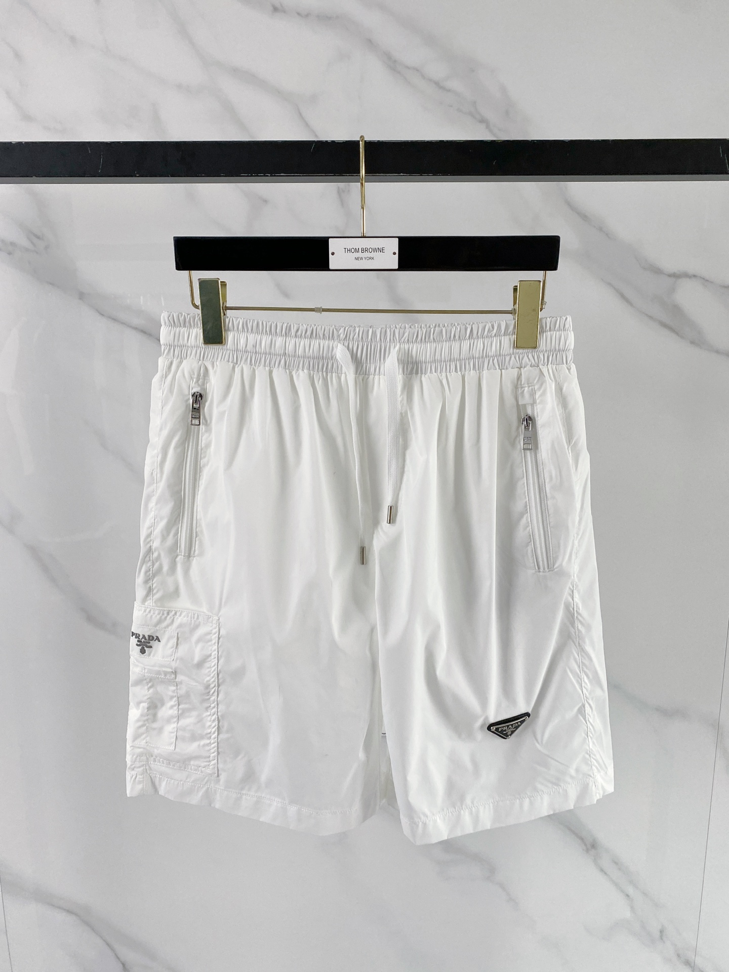 NO:848793,Prada Prada  2026ss summer classic triangle logo functional shorts, reconstructing summer casual aesthetics with minimalist lines. High-density anti-wrinkle nylon fabric is selected, which is smooth to the touch and has excellent breathability. It is light and burdenless to wear in summer; the elastic drawstring design at the waist is suitable for various body shapes and can be matched with  Equipped with double zipper side pockets and three-dimensional work patch pockets, the storage is full of security. The iconic enamel triangle logo on the front is the finishing touch, the webbing logo on the back has rigorous details, and the neat straight silhouette modifies the leg shape. Whether you are commuting in the city or traveling outdoors, you can easily create a high-end sense of relaxation.  Color Black White Size 48-56, prada, prada, shorts,19860909Prada 普拉达 2026ss夏季经典三角标机能短裤,以极简线条重构夏日休闲美学.甄选高密抗皱锦纶面料,触感顺滑且具备极佳透气性,夏日穿着轻盈无负担；腰头弹力抽绳设计适配各种身形,搭配双拉链侧袋与立体工装贴袋,收纳安全感拉满.正面标志性珐琅三角徽标点睛,背面织带标细节严谨,利落直筒版型修饰腿型,无论是都市通勤还是户外出行,皆能轻松演绎高阶松弛感. 颜色黑色 白色 码数48-56,,prada,prada,shorts,,Men's clothing