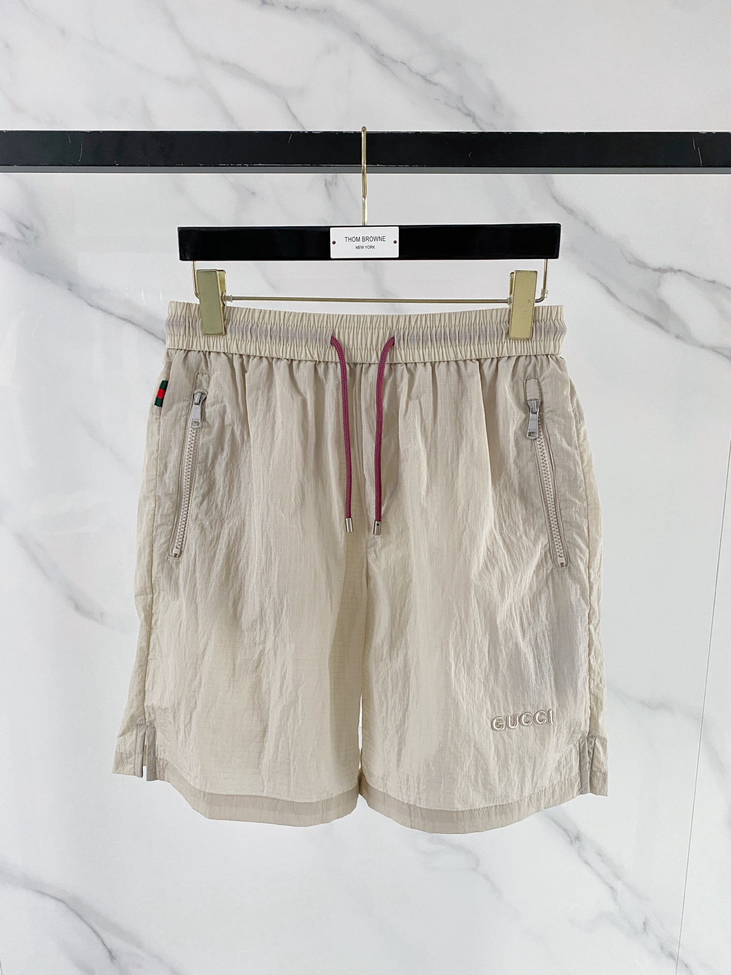 NO:848791,Gucci Gucci  The 2026ss summer limited edition contrasting color drawstring casual shorts cleverly combine the brand's classic webbing elements with refreshing functional style. They are available in navy blue/off-white and are suitable for a variety of summer styles. Made of high-density wrinkled nylon fabric, they are lightweight and breathable. The upper body is draped and stylish, without fear of stuffiness and wrinkles; the waistband is designed with a contrasting pink drawstring  Designed with classic red and green webbing details on the side, the brand genes can be recognized at a glance. The front zipper pocket is both practical and neat. The GUCCI letter logo on the front and the metal badge pocket on the back are low-key. The loose straight version modifies the leg shape. Whether you are commuting in the city or traveling on vacation, you can easily create a relaxed and noble summer style.  Color: navy blue, off-white, size 48-56,,gucci,shorts,19860909Gucci 古奇 2026ss夏季限定撞色抽绳休闲短裤,将品牌经典织带元素与清爽机能风巧妙融合,藏青/米白双色可选,适配多元夏日风格.甄选高密皱感尼龙面料打造,自带轻量透气属性,上身垂坠有型,无惧闷热与褶皱；腰头撞色粉调抽绳设计,搭配侧边经典红绿织带细节,一眼识别品牌基因.前侧拉链口袋兼顾实用与利落,正面GUCCI字母标识与背面金属徽章口袋低调点题,宽松直筒版型修饰腿型,无论是都市通勤还是度假出行,都能轻松塑造松弛显贵的夏日格调. 颜色藏青 米白 码数48-56,,gucci,shorts,,Men's clothing