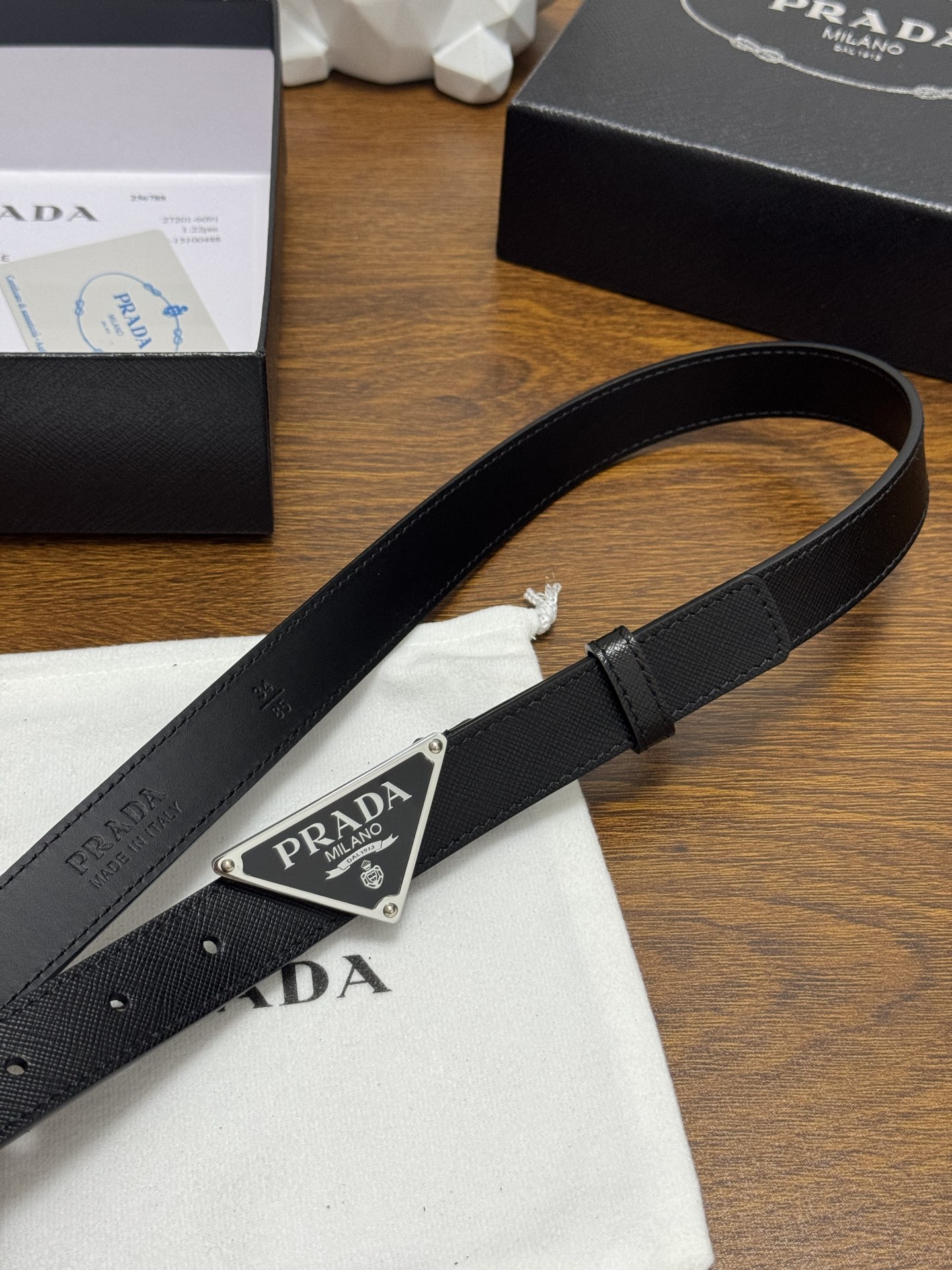 PRADA 2.5cm 颜色：黑色十字纹皮革腰带风格简约之作醒目装饰涂珐琅三角形金属徽标柔软自然，赋予设