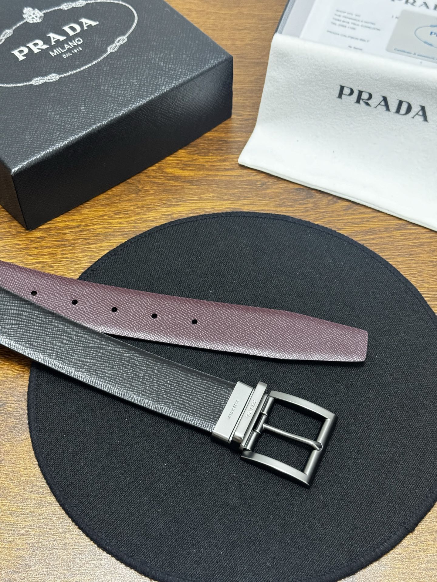 PRADA   3.5cm     黑/枣红   砂枪扣十字纹牛皮革腰带设计简约精致，亮眼的金属铜质工艺