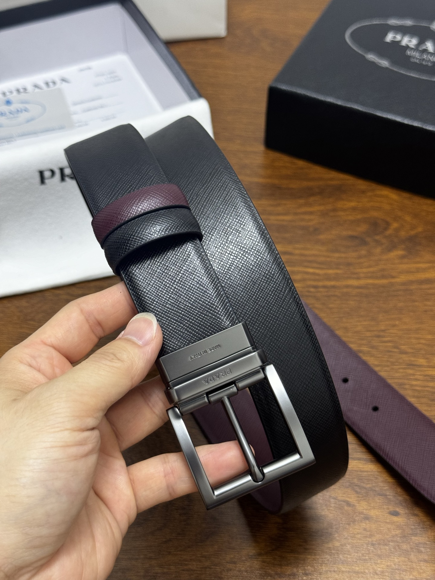PRADA   3.5cm     黑/枣红   砂枪扣十字纹牛皮革腰带设计简约精致，亮眼的金属铜质工艺