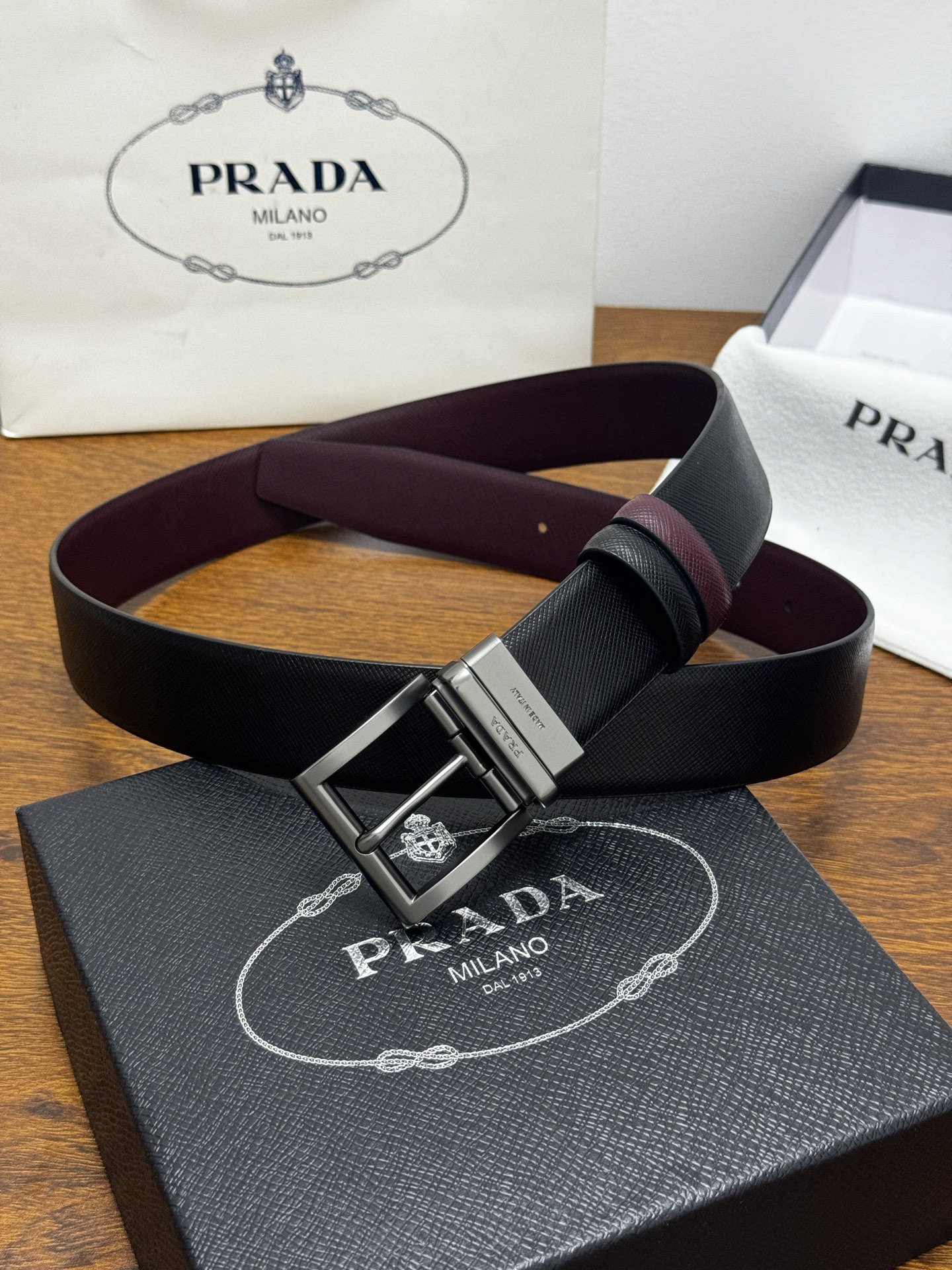 PRADA   3.5cm     黑/枣红   砂枪扣十字纹牛皮革腰带设计简约精致，亮眼的金属铜质工艺