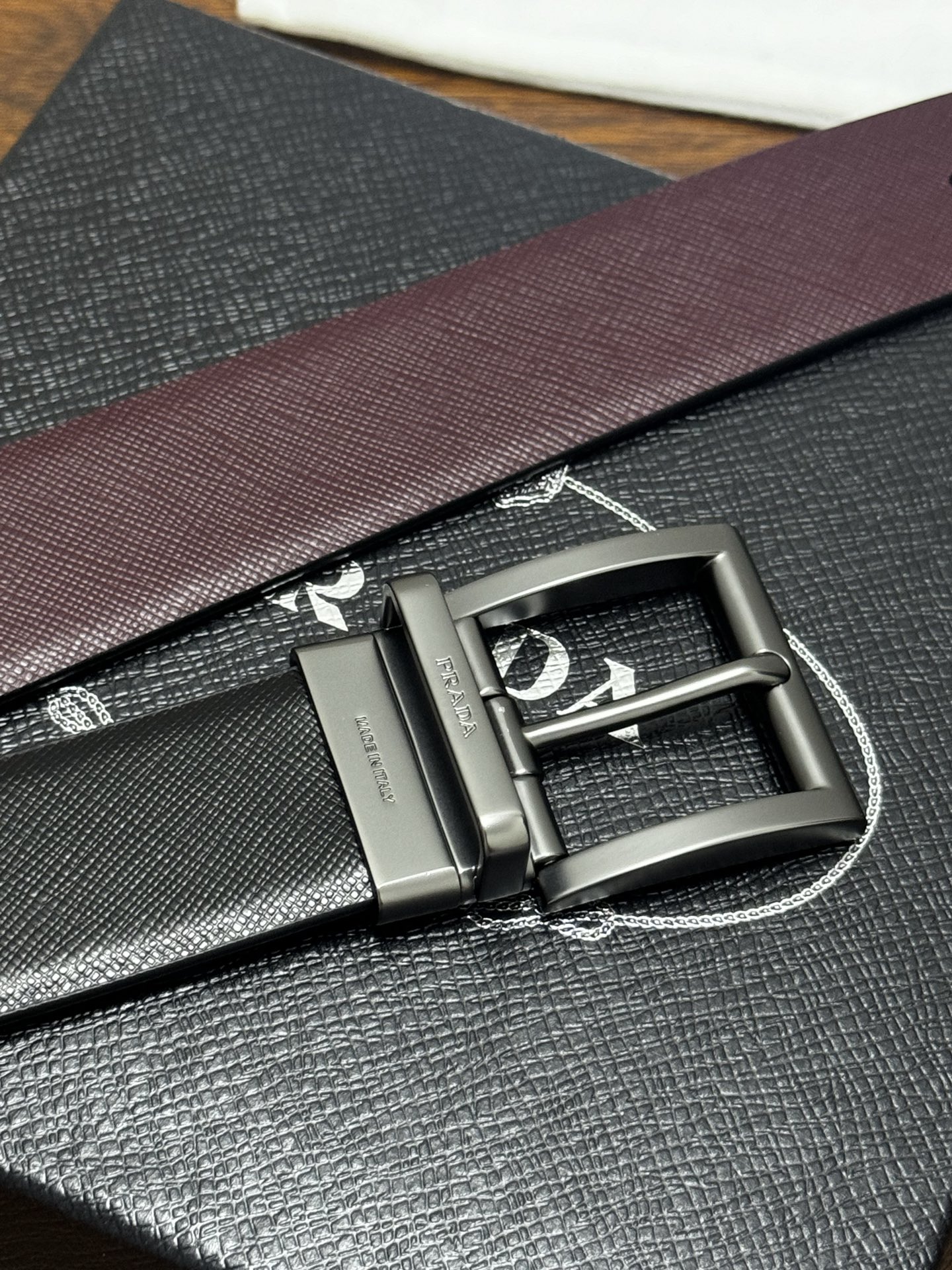 PRADA   3.5cm     黑/枣红   砂枪扣十字纹牛皮革腰带设计简约精致，亮眼的金属铜质工艺