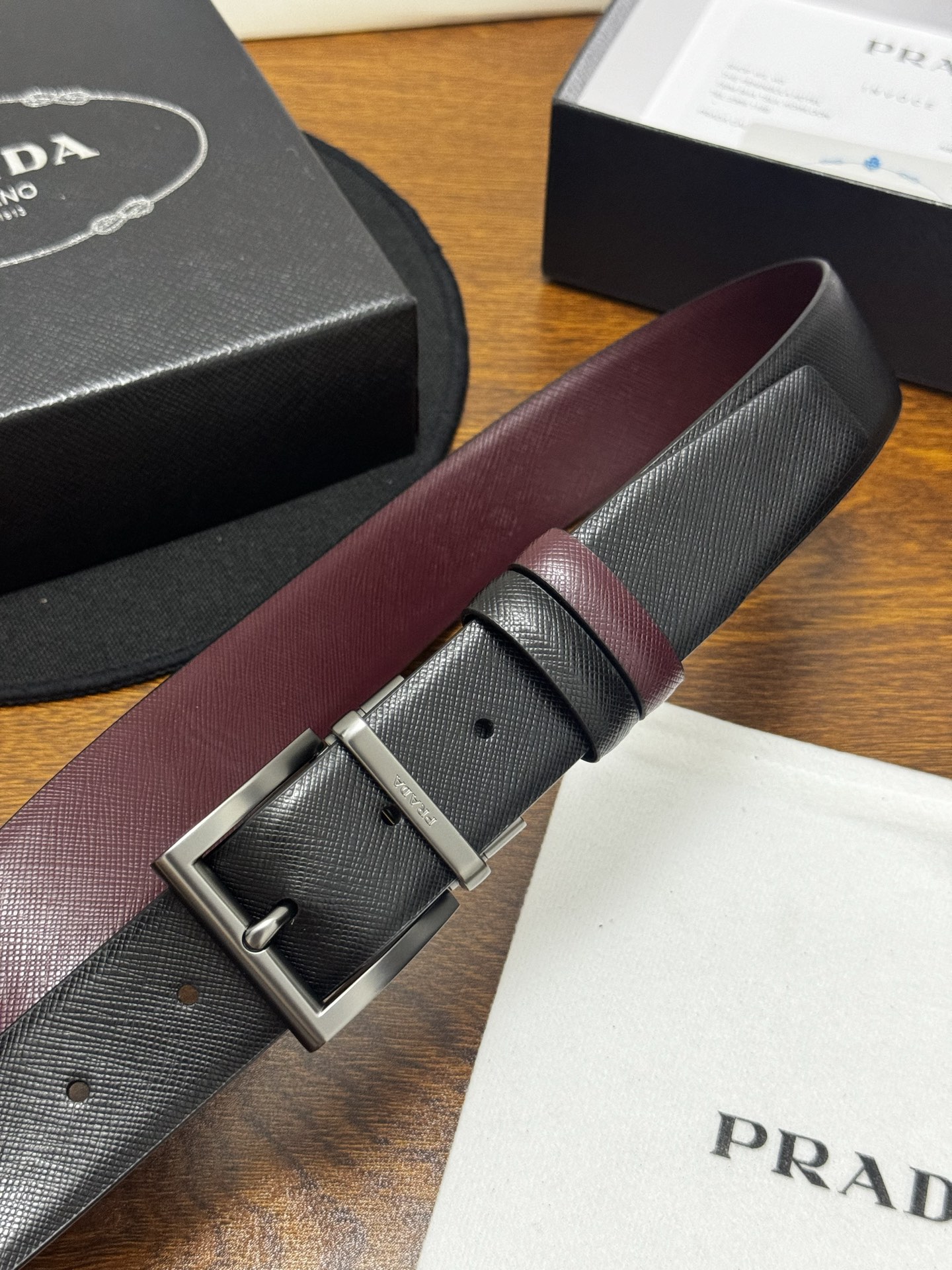 PRADA   3.5cm     黑/枣红   砂枪扣十字纹牛皮革腰带设计简约精致，亮眼的金属铜质工艺