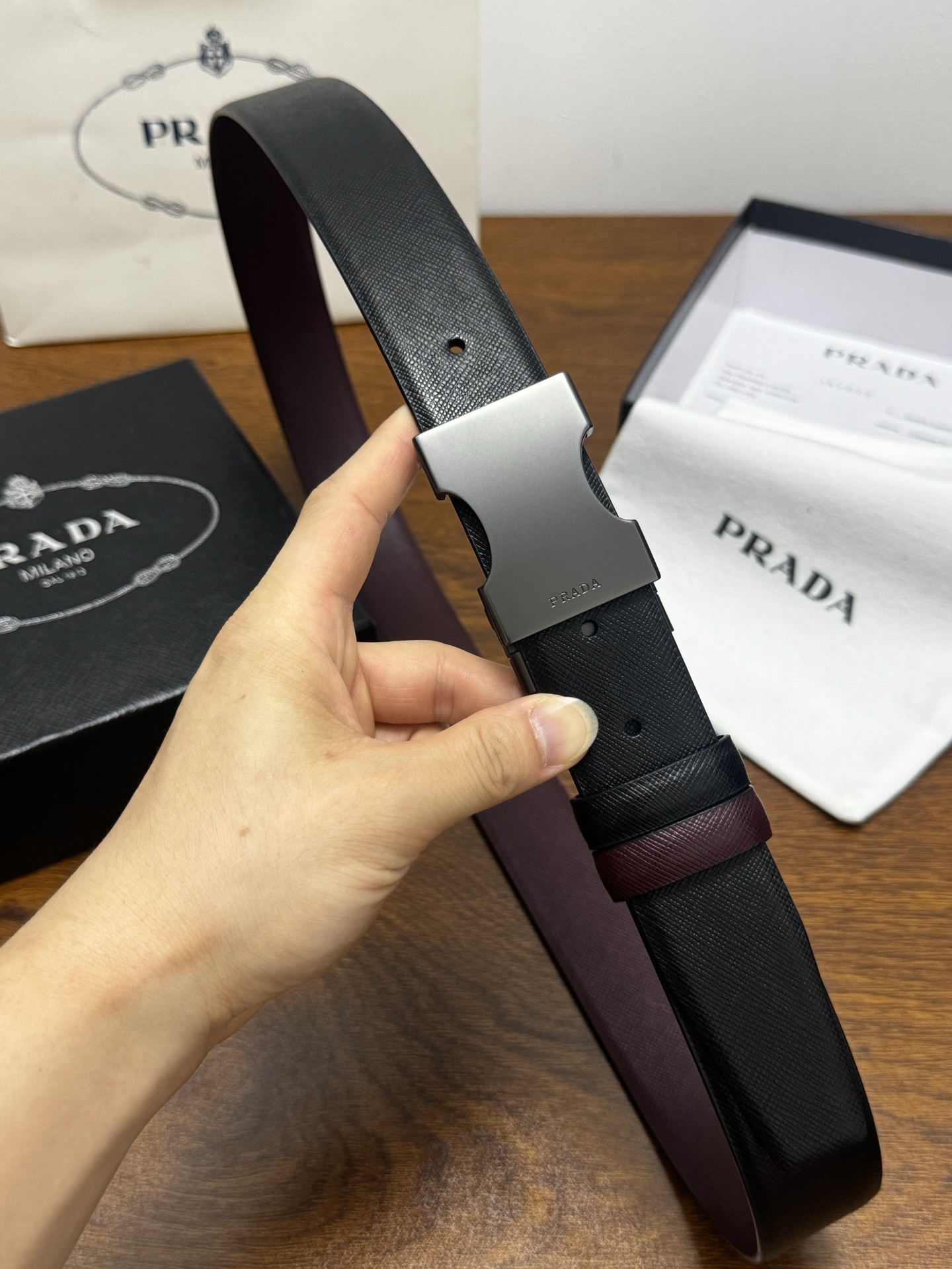 PRADA 3.5cm 黑/枣红 砂枪扣 十字纹牛皮革腰带设计简约精致,亮眼的金属铜质工艺扣头。柔软自然 PRADA 3.5cm 黑/枣红 砂枪扣 十字纹牛皮革腰带设计简约精致,亮眼的金属铜质工艺扣头。柔软自然