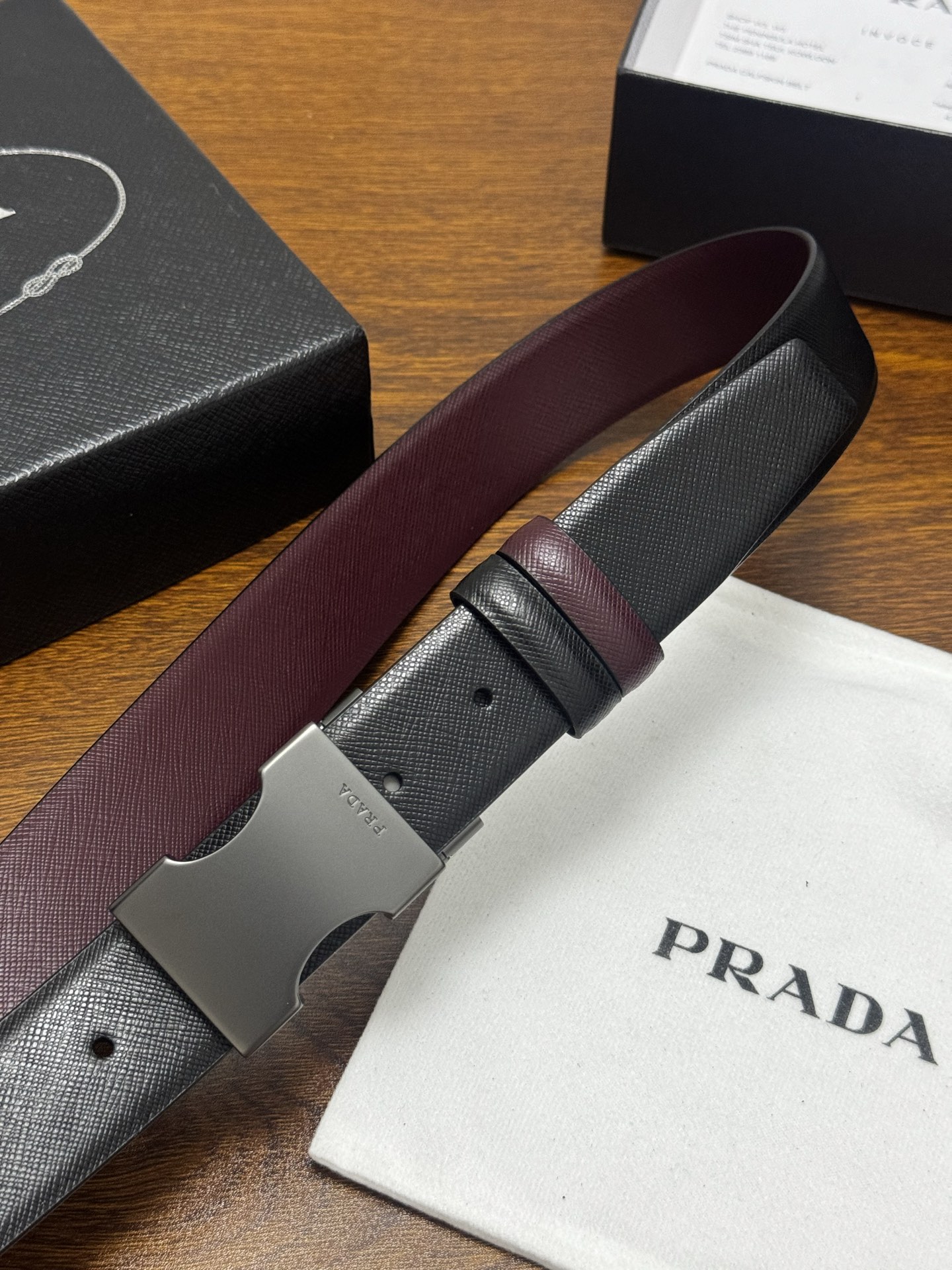 PRADA 3.5cm 黑/枣红 砂枪扣 十字纹牛皮革腰带设计简约精致,亮眼的金属铜质工艺扣头。柔软自然 PRADA 3.5cm 黑/枣红 砂枪扣 十字纹牛皮革腰带设计简约精致,亮眼的金属铜质工艺扣头。柔软自然